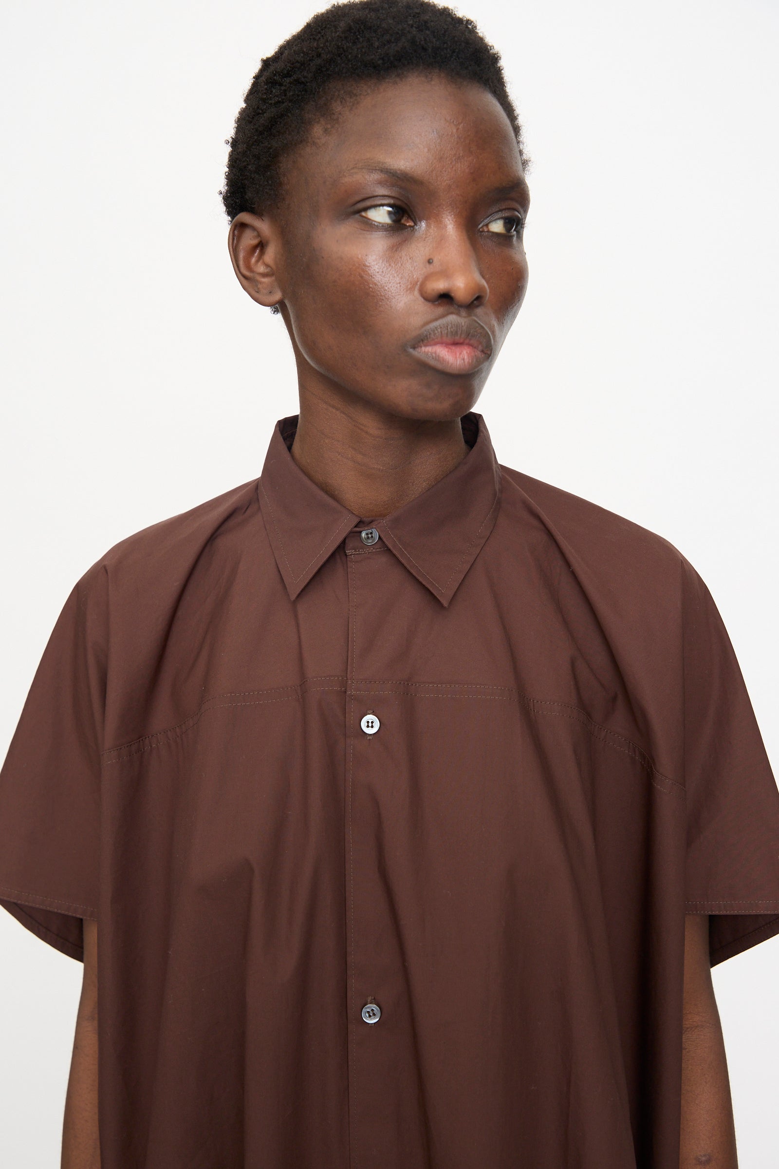 A person with short hair wears the Sofie D'Hoore Duchy Dress in Cacao and looks slightly to the side against a plain white background.