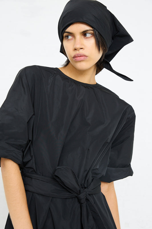 Person wearing a black Sofie D'Hoore Duke Dress with Lace Hem and headscarf, looking to the side.
