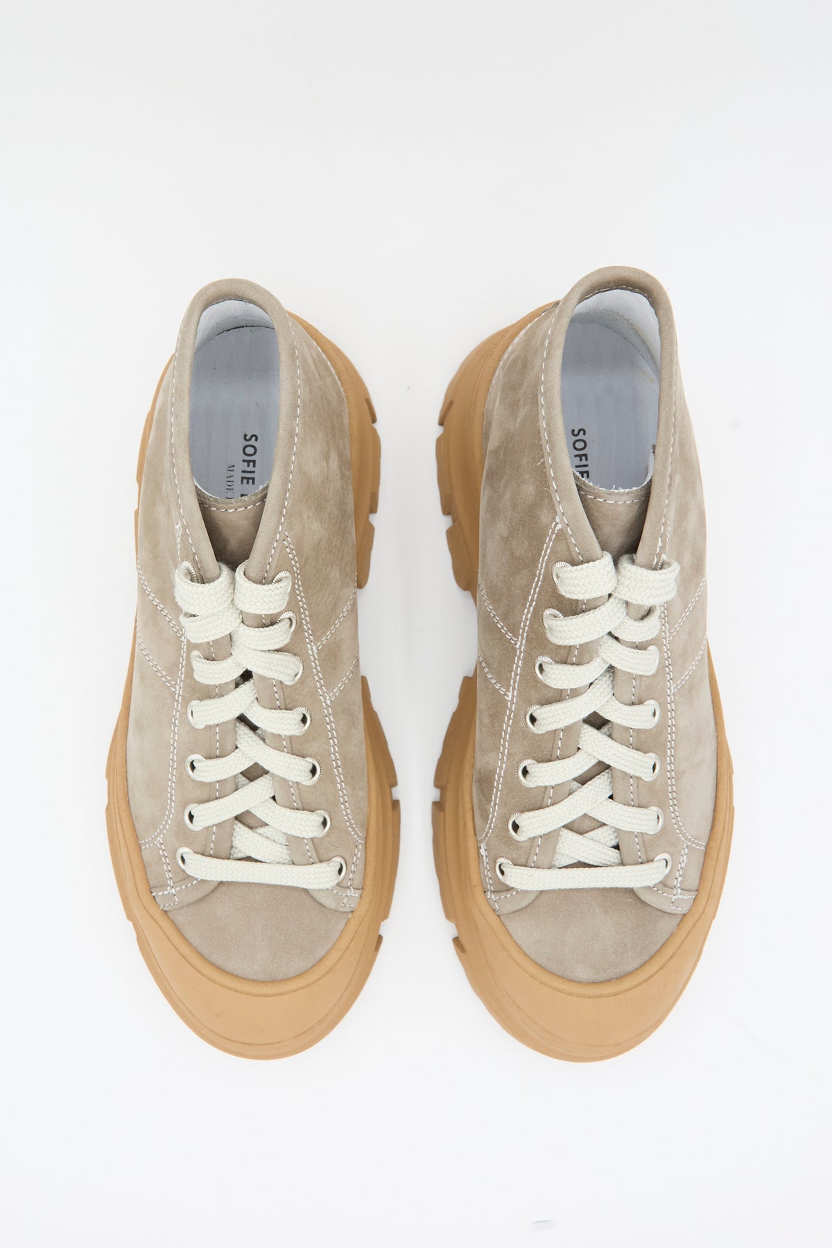 Top-down view of a pair of beige nubuck Sofie D’Hoore Fairway Sneaker in Argilla and Camel with thick camel-colored lugged rubber soles and cream-colored laces.