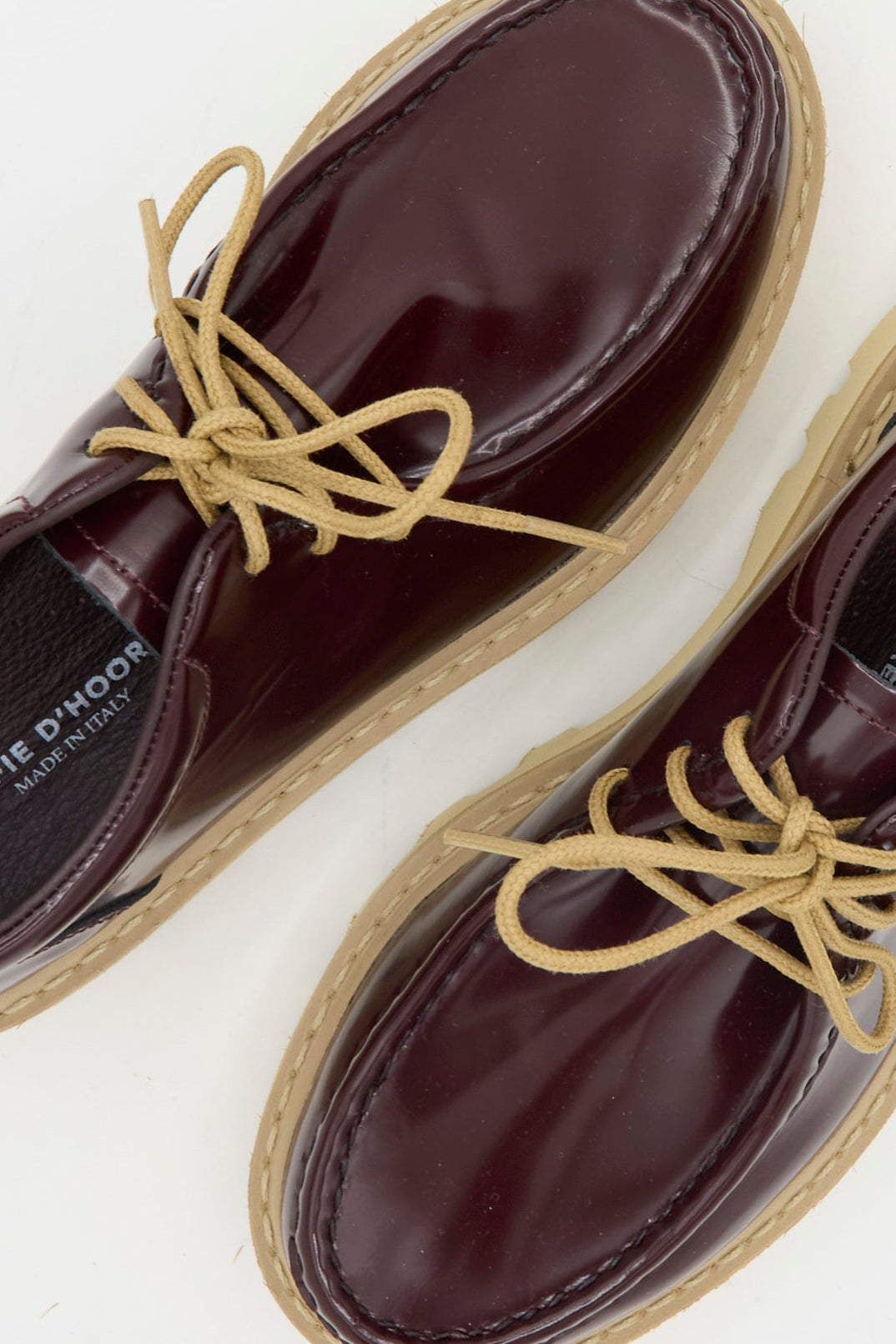 The Sofie D'Hoore Falcone Wallabee Shoe in Mahogany features burgundy patent leather, beige laces, and tan rubber soles, shown from above on a white background.