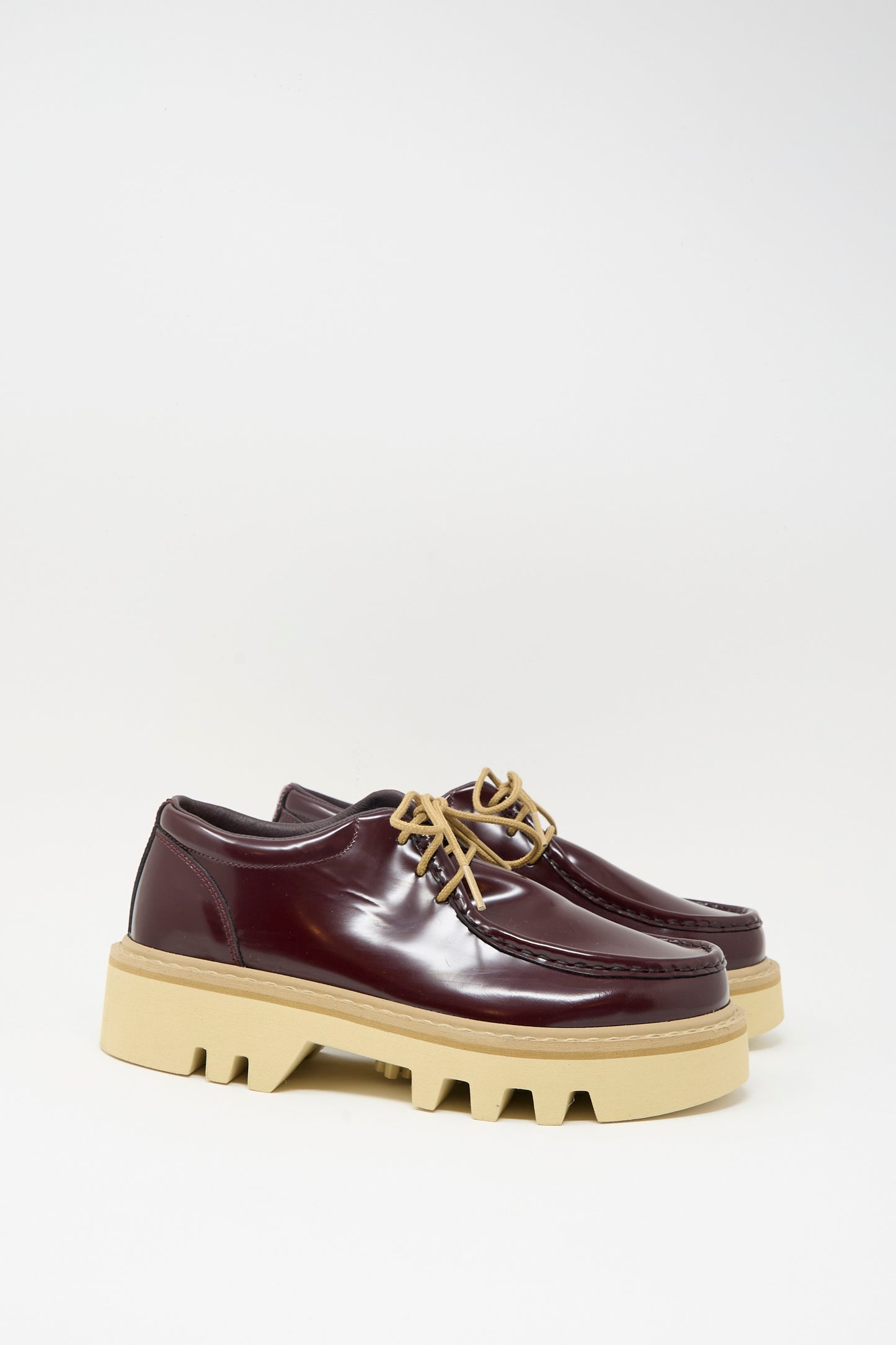 The Sofie D'Hoore Falcone Wallabee Shoe in Mahogany features glossy patent leather, tan laces, and beige chunky rubber soles, shown against a plain white background.