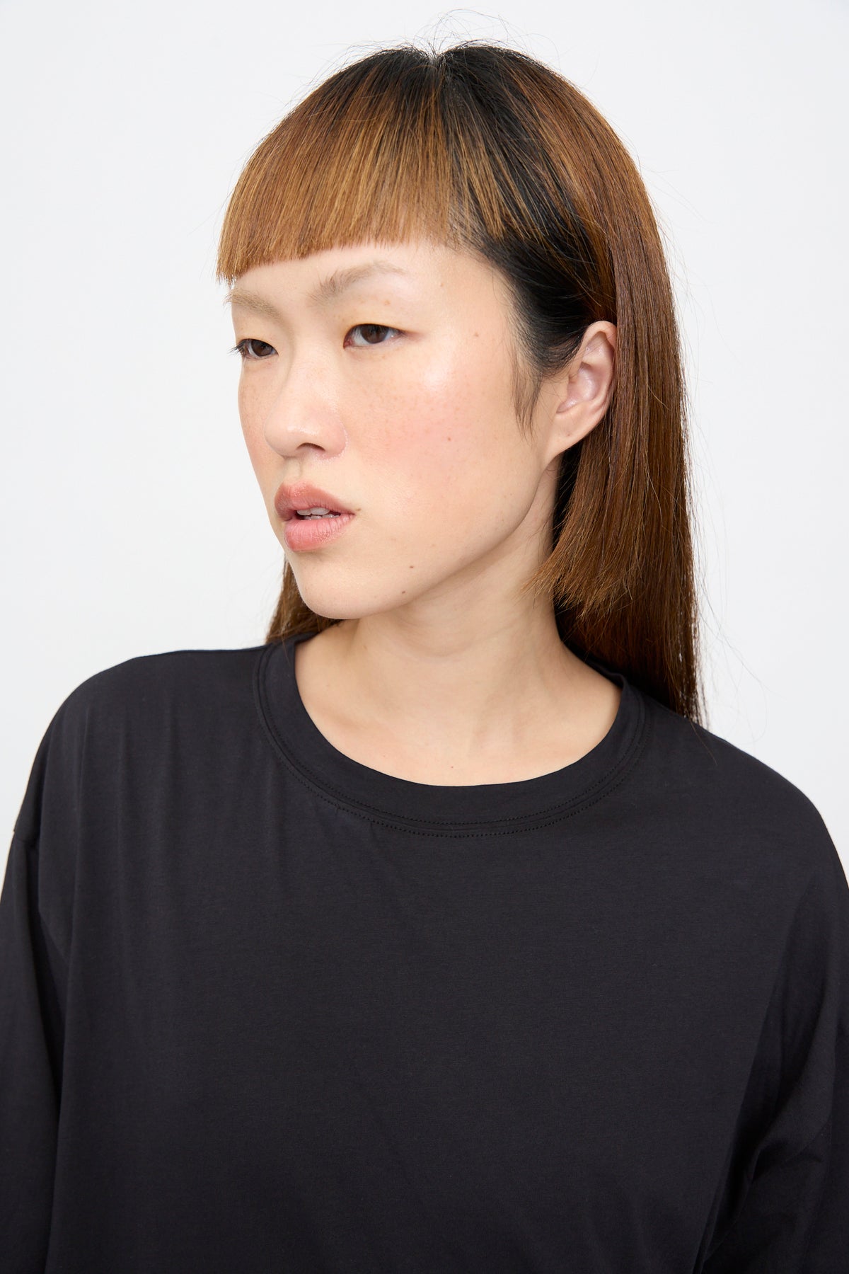A person wearing a plain black, oversized Sofie D’Hoore Fine Cotton Jersey Toledo Tee in Cosmos with a crew neck.