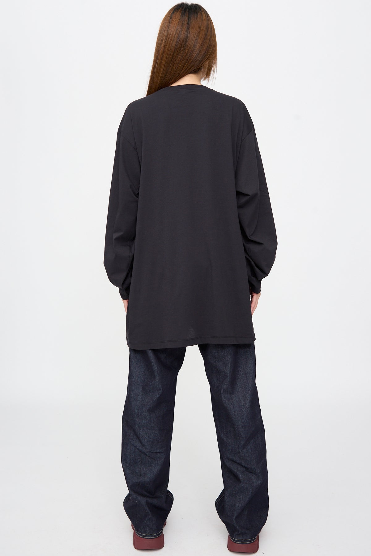 A person seen from behind, wearing an oversized black Fine Cotton Jersey Toledo Tee in Cosmos and dark blue jeans.