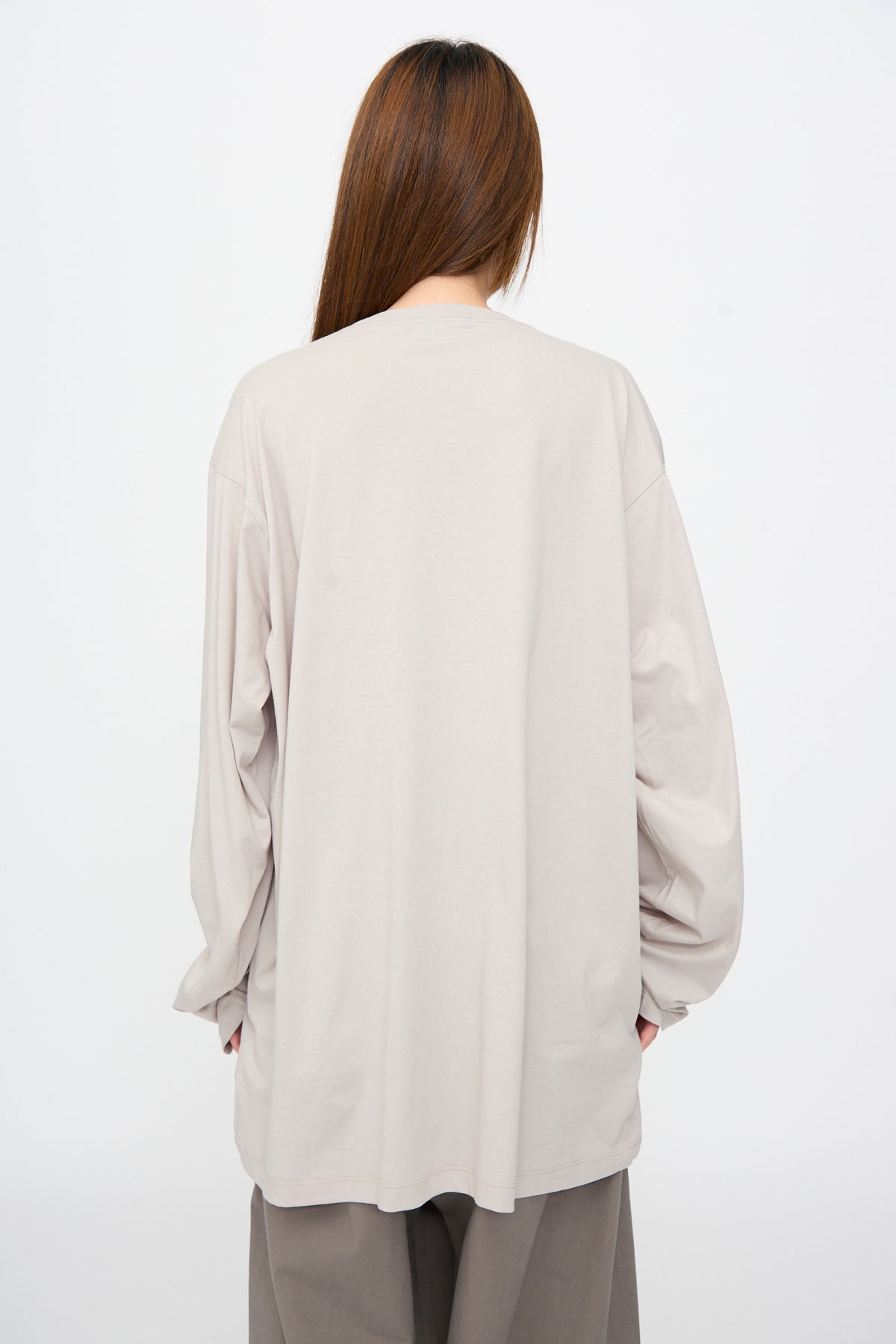 Back view of a person wearing an oversized, long-sleeve light grey Fine Cotton Jersey Toledo Tee in Powder.