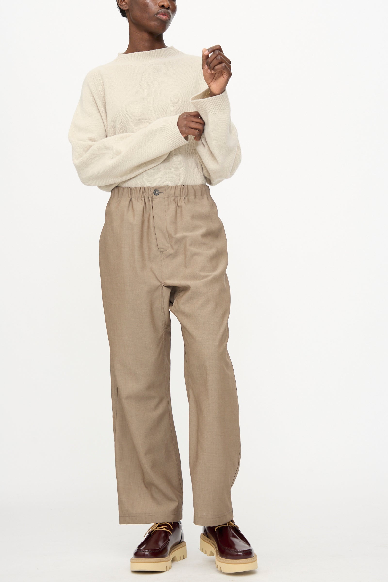 A person wearing a cream sweater, Sofie D'Hoore Light Mohair Wool Pinot Pant in Quartz, and brown platform shoes stands against a plain white background.
