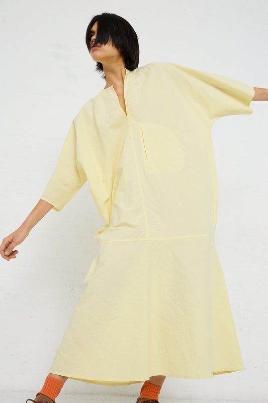 A person in a yellow oversized Linen Cotton Delfi Dress in Pastis by Sofie D'Hoore striking a dynamic pose against a white background.