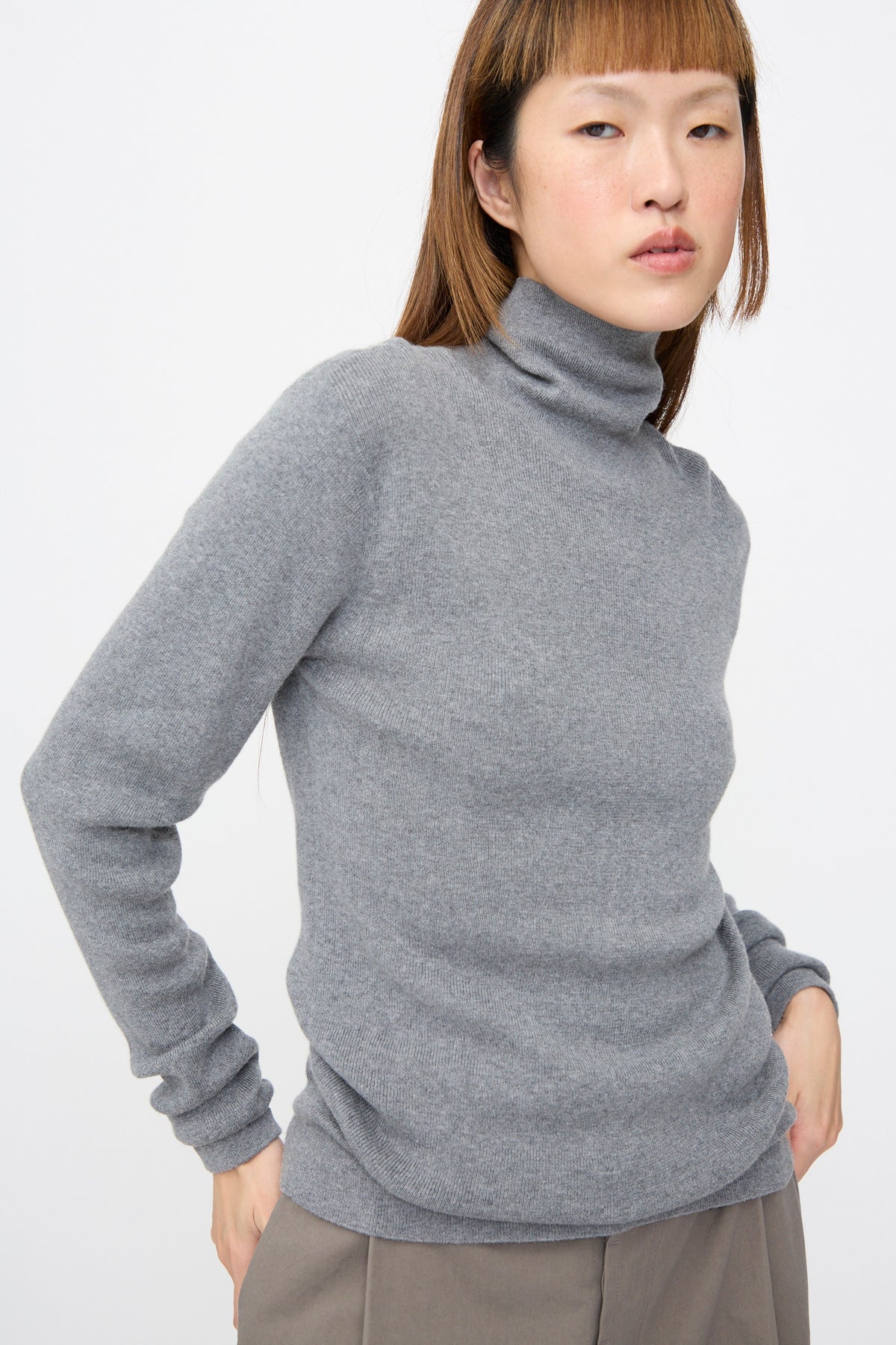 Person wearing a grey, rib-knit turtleneck Malika Sweater in Grey Melange by Sofie D’Hoore.