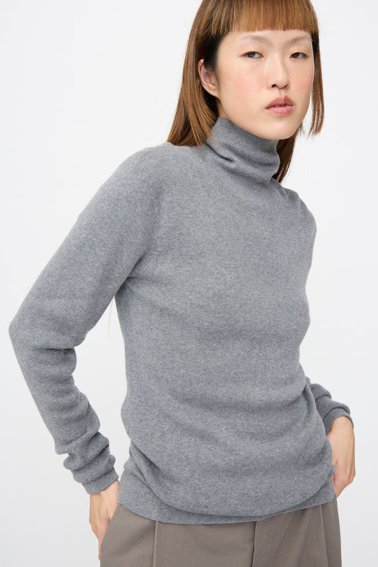 Person wearing a grey, rib-knit turtleneck Malika Sweater in Grey Melange by Sofie D’Hoore.
