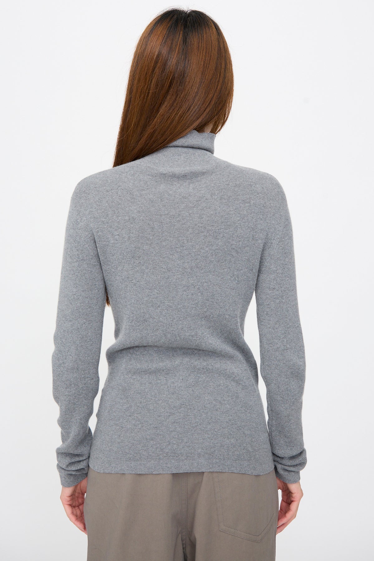 Back view of a person wearing a grey rib-knit turtleneck Malika Sweater in Grey Melange.