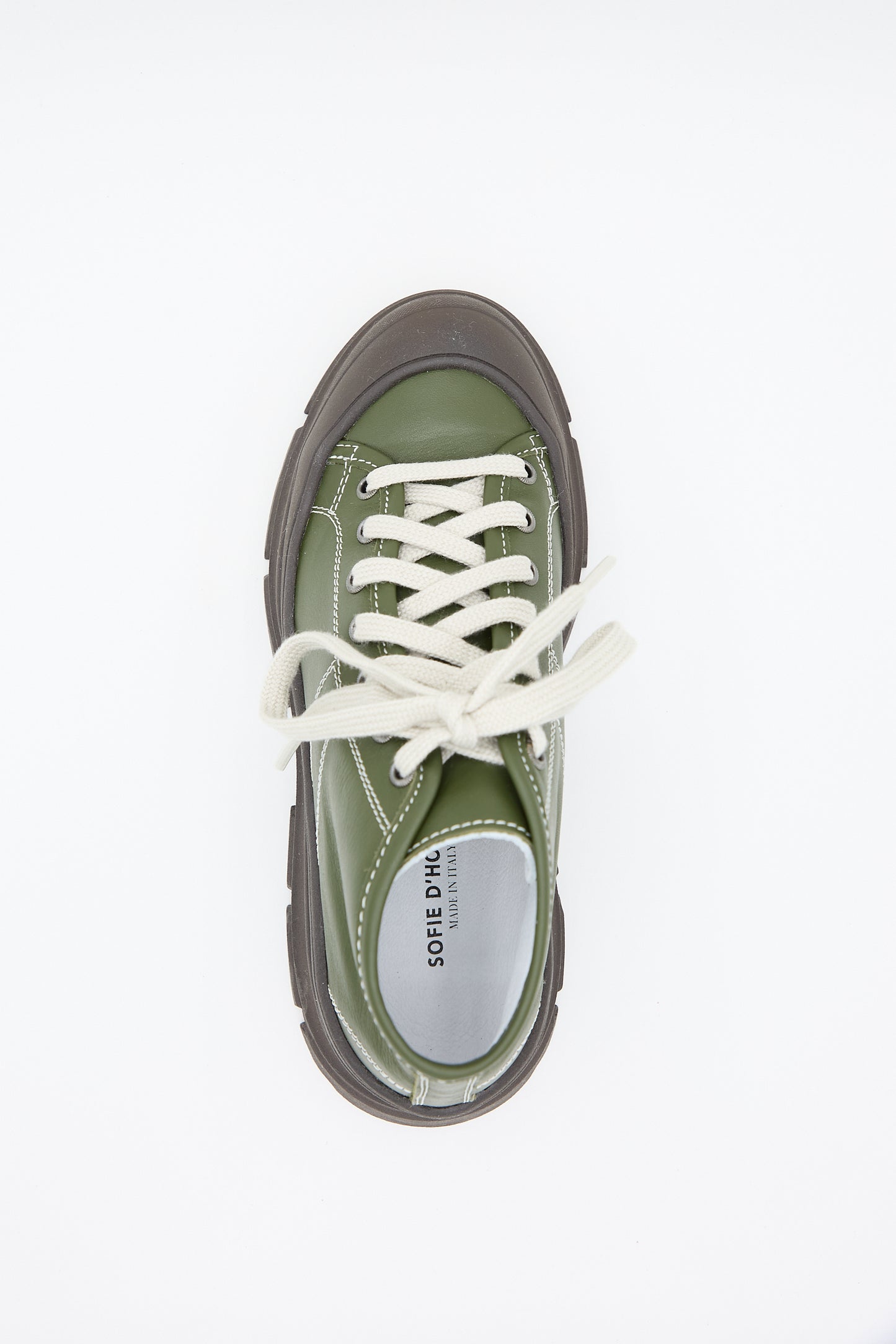 Top view of the Nappa Leather Fairway Sneaker in Forest by Sofie D'Hoore, a green lace-up platform sneaker featuring a white label reading "SORE, MIX, Explorations." The shoe showcases nappa leather craftsmanship with a brown sole, rubber cap toe, and white laces.