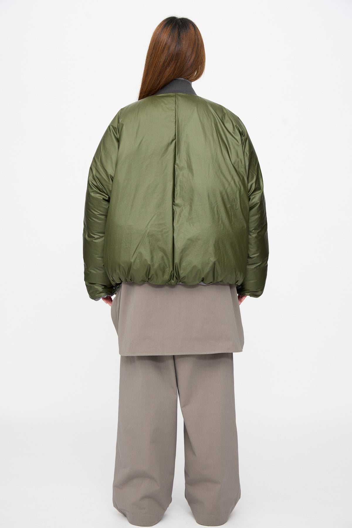 Back view of a person wearing a khaki Origin Down Jacket in Charcoal and Khaki over a long taupe top and matching wide-leg trousers.