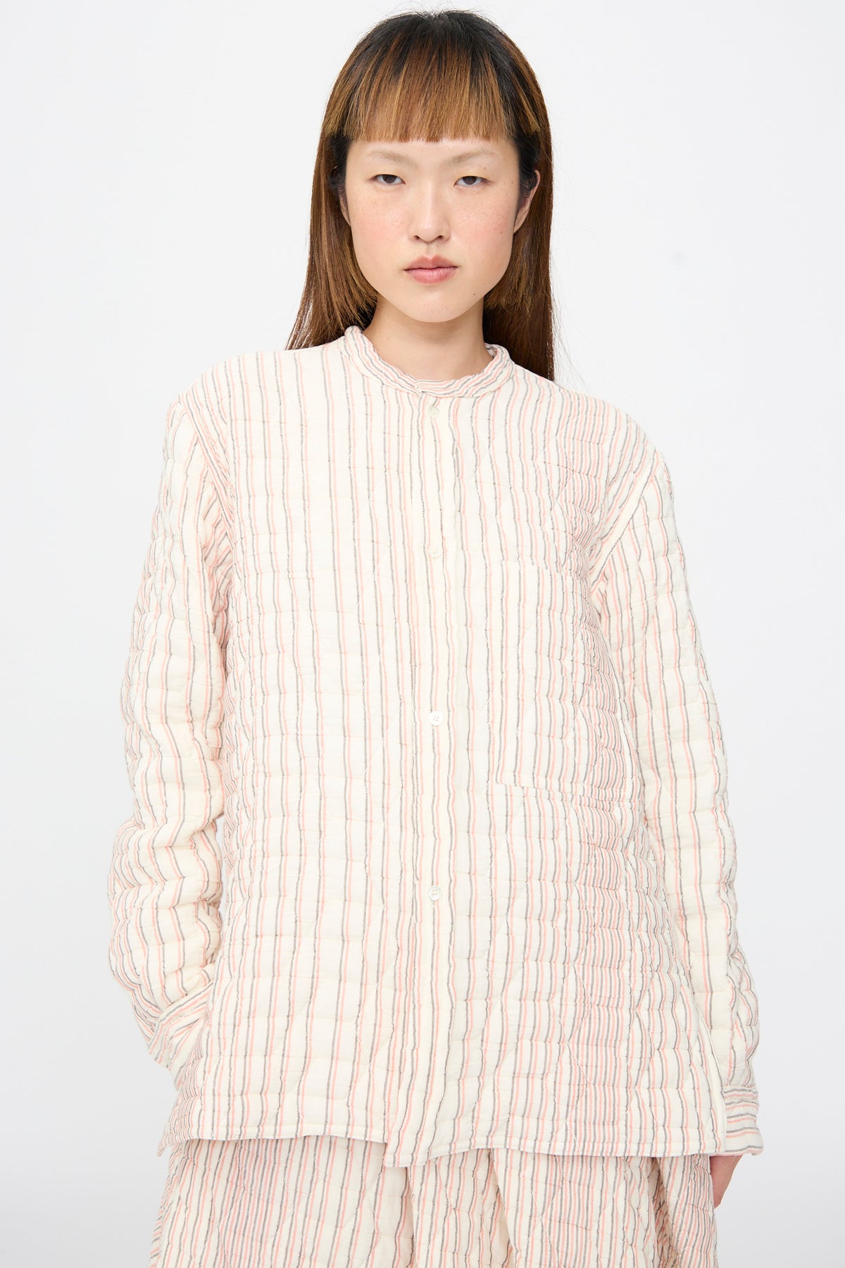 A model wears a Sofie D’Hoore Quilted Cotton Bela Shirt in Red Stripe, a relaxed-fit, long-sleeved, button-down shirt with a quilted texture and vertical stripe pattern.