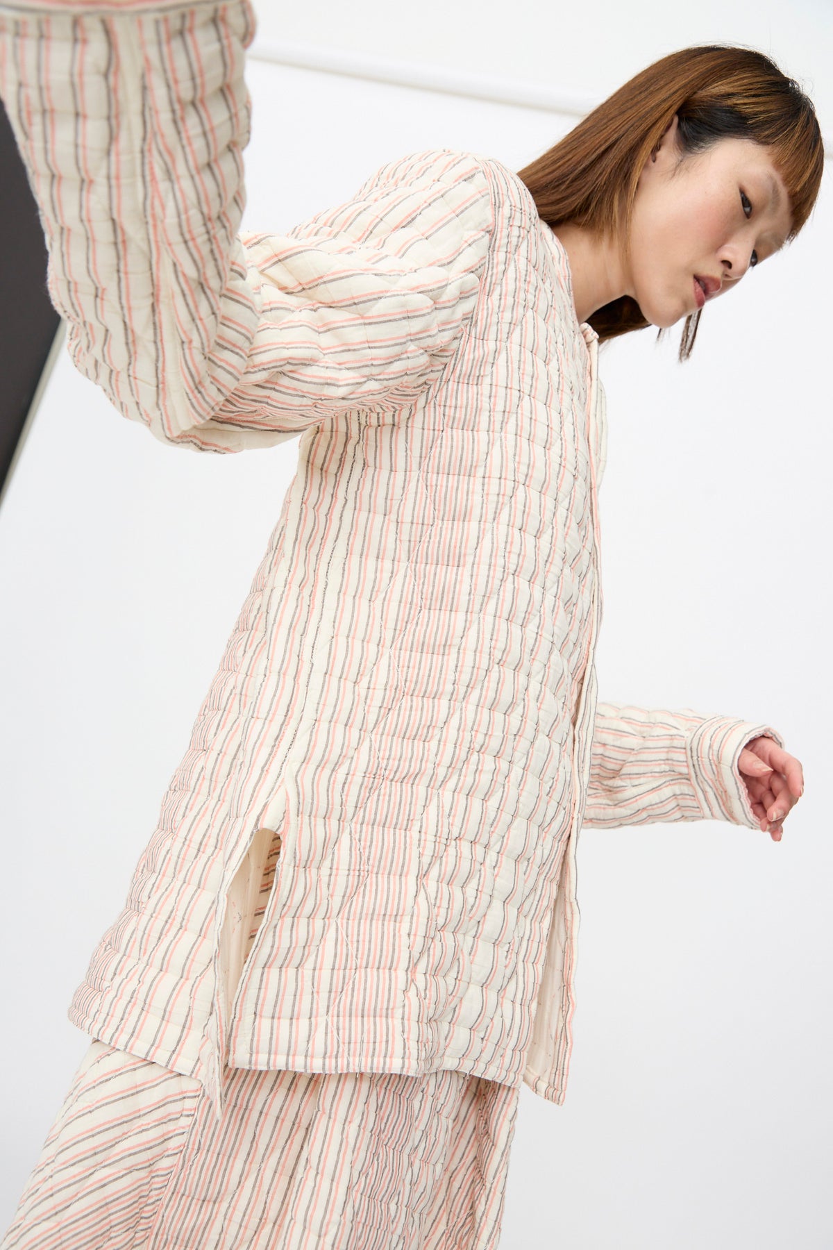 A person wearing a Sofie D’Hoore Quilted Cotton Bela Shirt in Red Stripe and matching pants with vertical red and blue stripes in a relaxed fit.