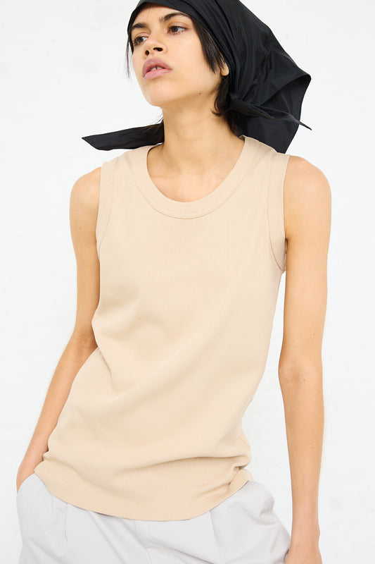 Woman in a Sofie D'Hoore nude rib knit tank top with a black headscarf looking to the side.