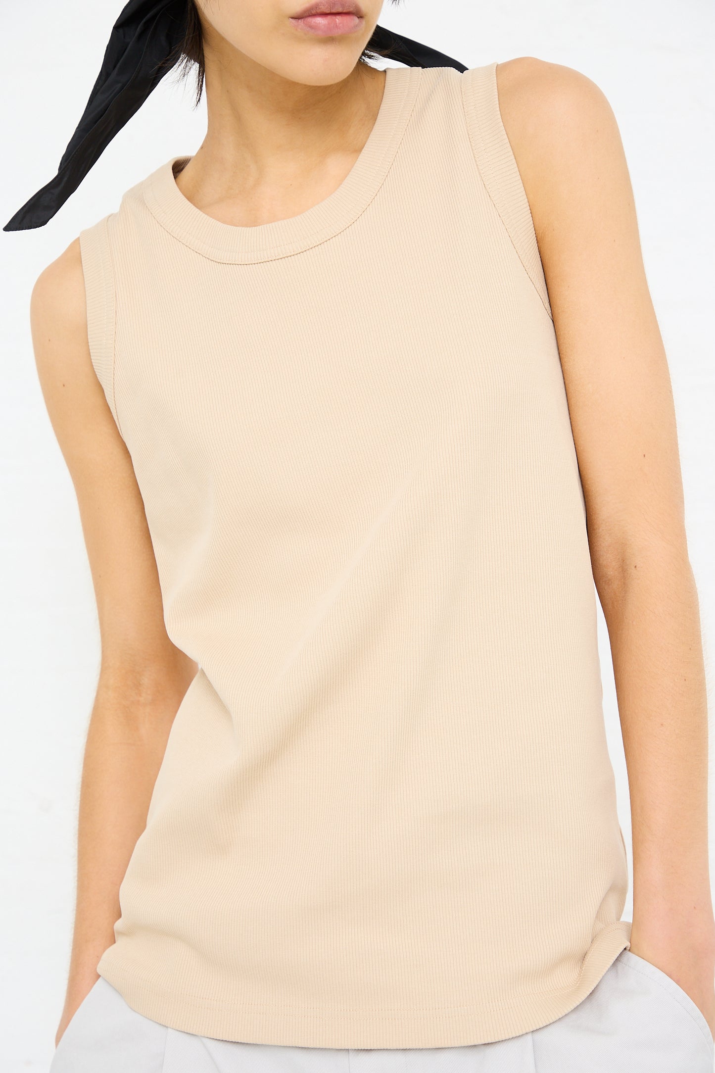 Woman wearing a Sofie D'Hoore rib knit tank in nude with a raven on her shoulder.