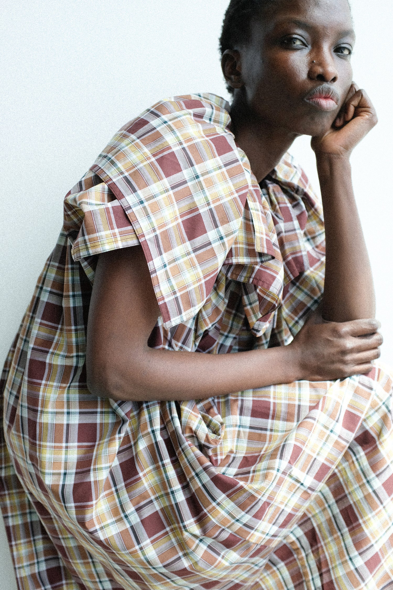 Person wearing Sofie D'Hoore's Cotton Batiste Check Dolabella Dress in Toffee with a neutral background.