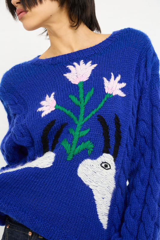 Woman wearing a Sofio Gongli Animal Floral Sweater in Blue with a white and pink floral design and a depiction of a rabbit.