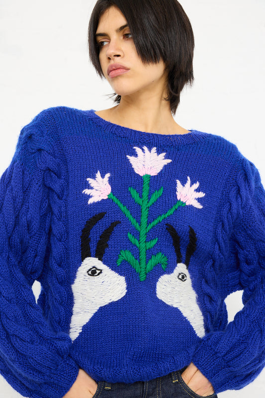 A woman in a Sofio Gongli Animal Floral Sweater in Blue, looking off to the side.