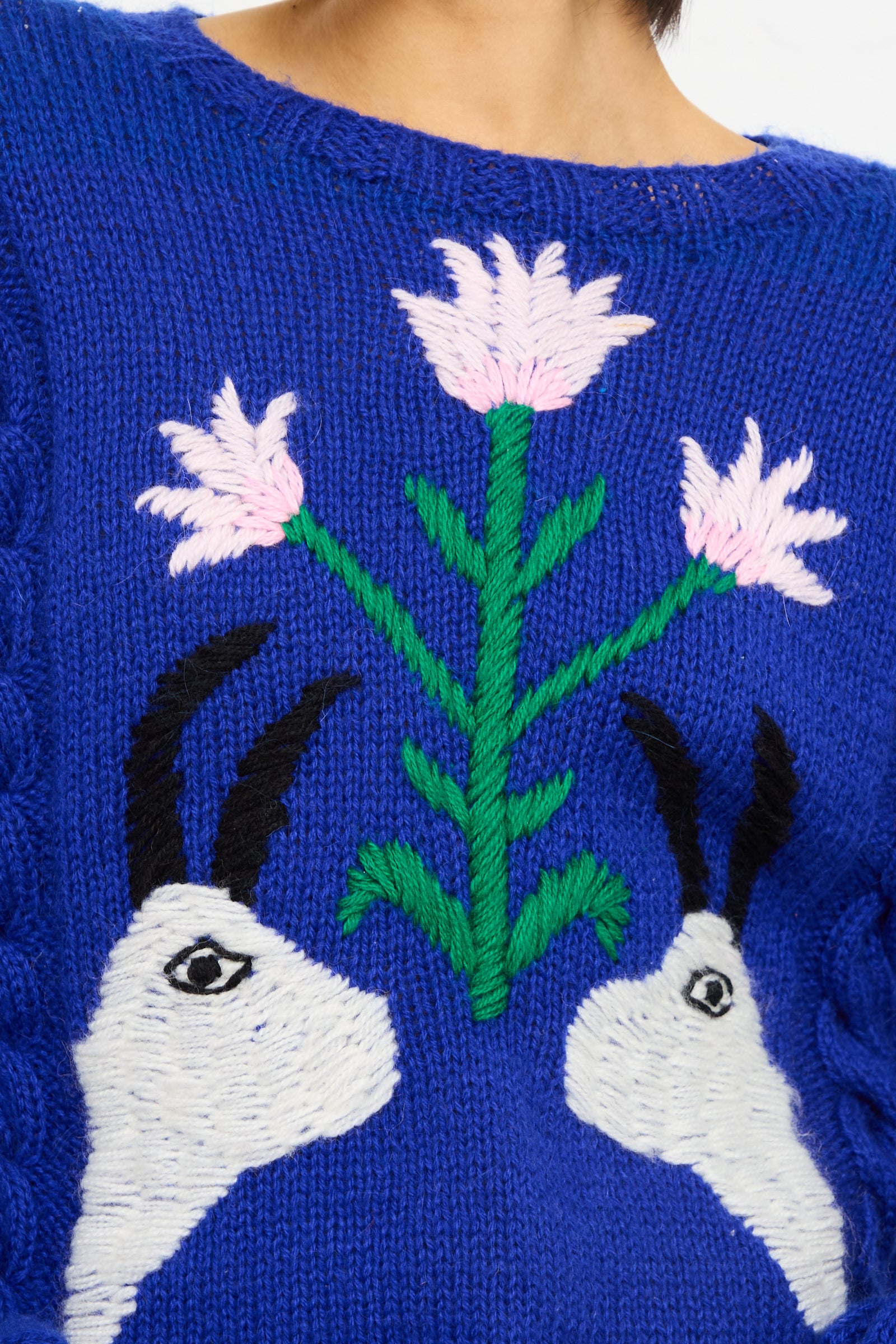 Close-up of a Sofio Gongli Animal Floral Sweater in Blue with a knitted design featuring two white rabbits and a pink floral pattern.