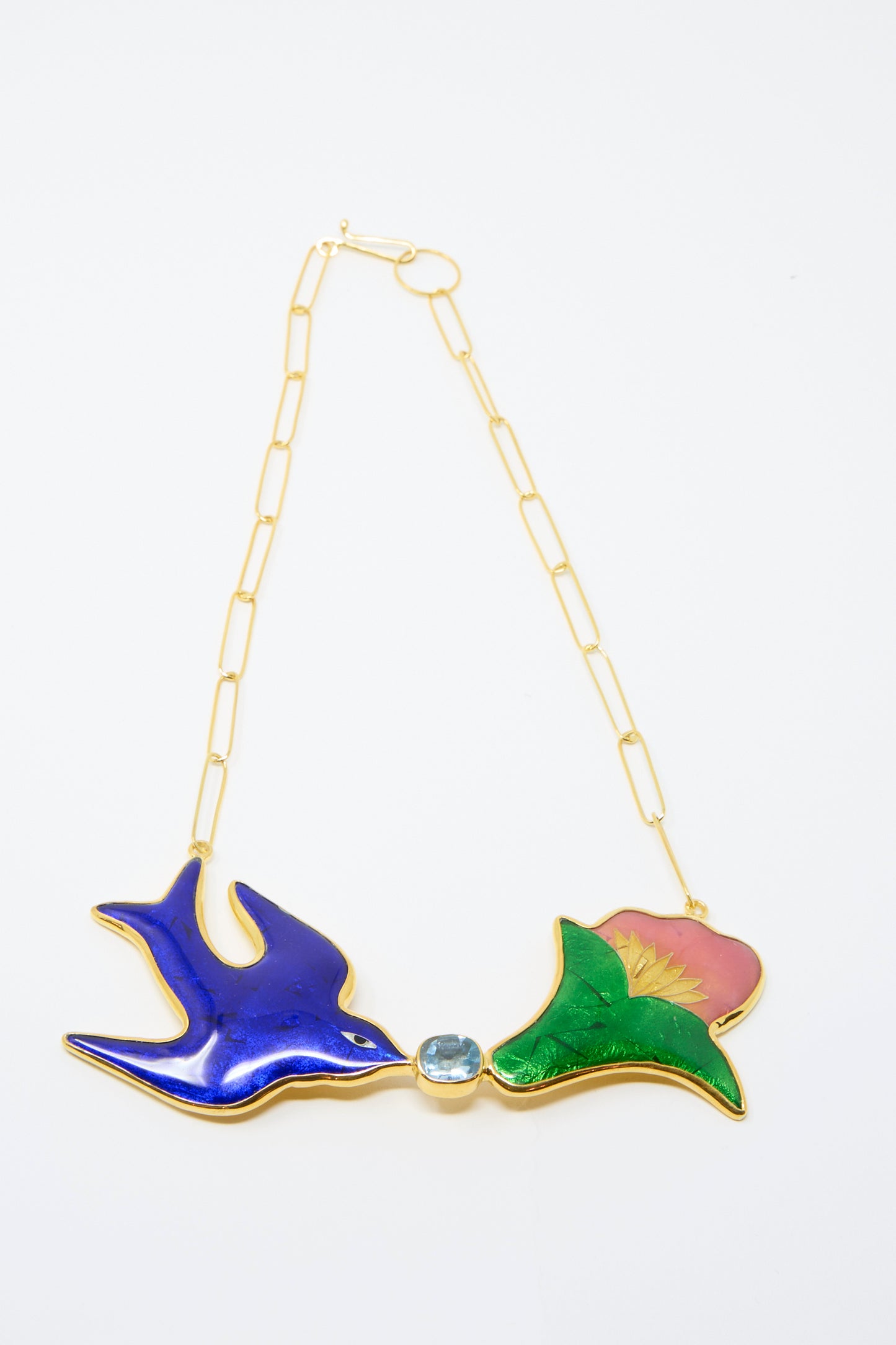 The Bird and Flower Necklace by Sofio Gongli features a 4K gold-plated design with a blue bird and pink flower connected by a gleaming Corundum stone, against a white background. 