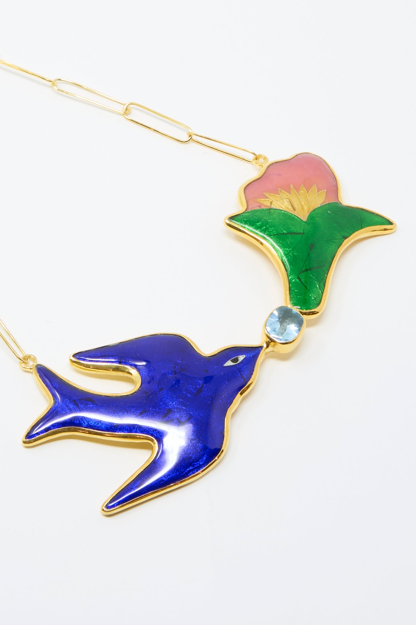 The Sofio Gongli Bird and Flower Necklace is a 14K Gold Plated cloisonné piece featuring a pendant with a blue bird and green-pink flower, linked by a gold chain.