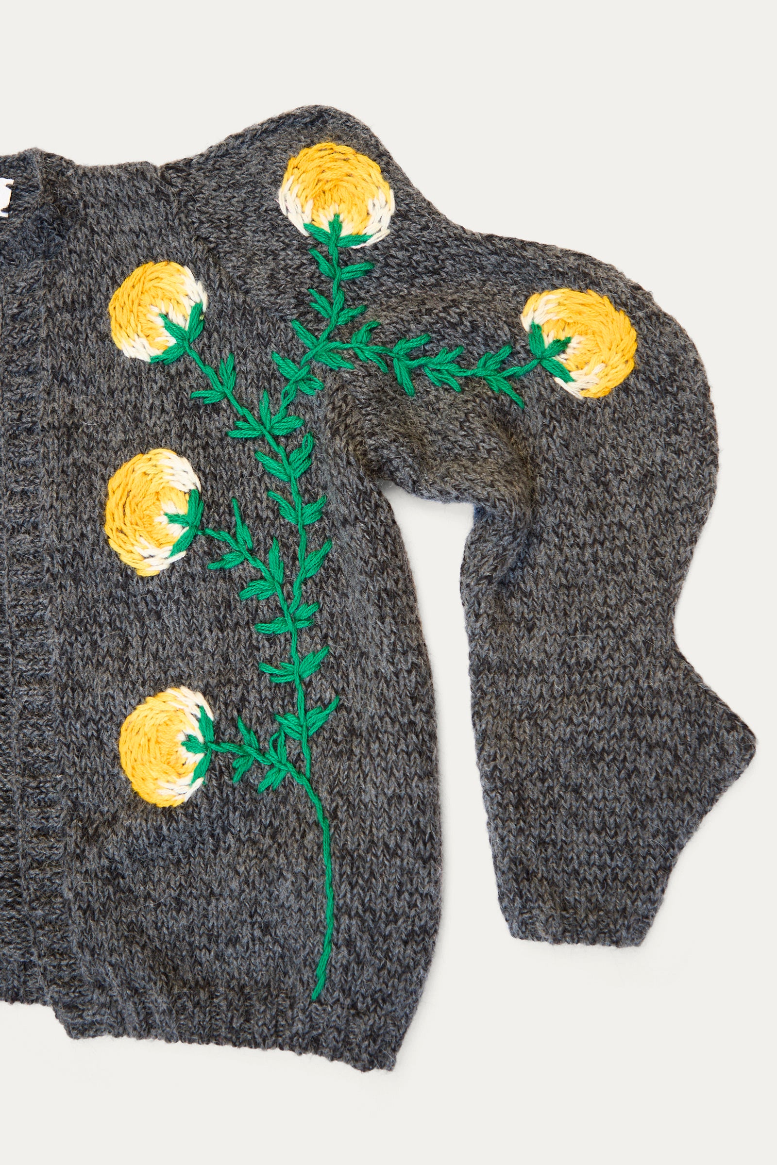 The Sofio Gongli Cardigan with Yellow Flower in Grey is a hand-knit sweater crafted from a soft mohair wool blend, featuring delicate yellow flower embroidery and green stems on the front.