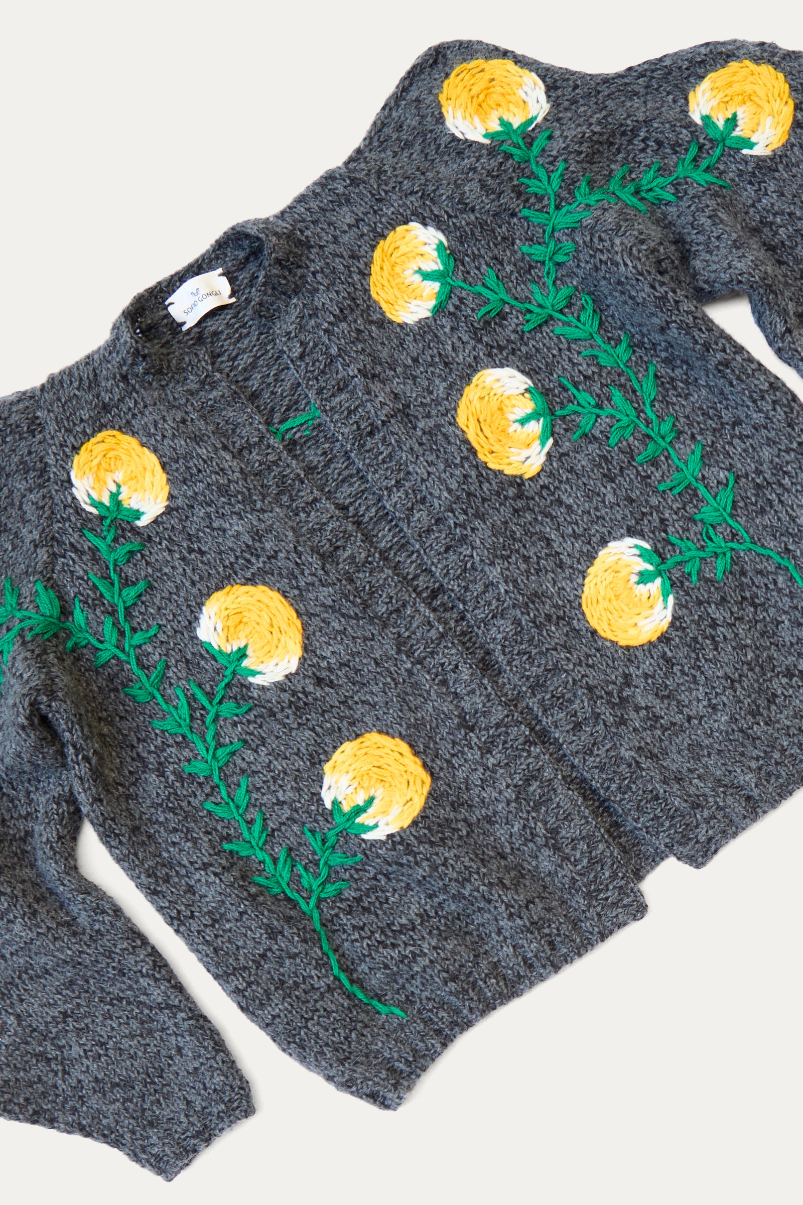 The Sofio Gongli Cardigan with Yellow Flower in Grey is a hand-knit piece featuring a charming gray mohair wool blend, adorned with delicate yellow flower embroidery and green stems on the front.