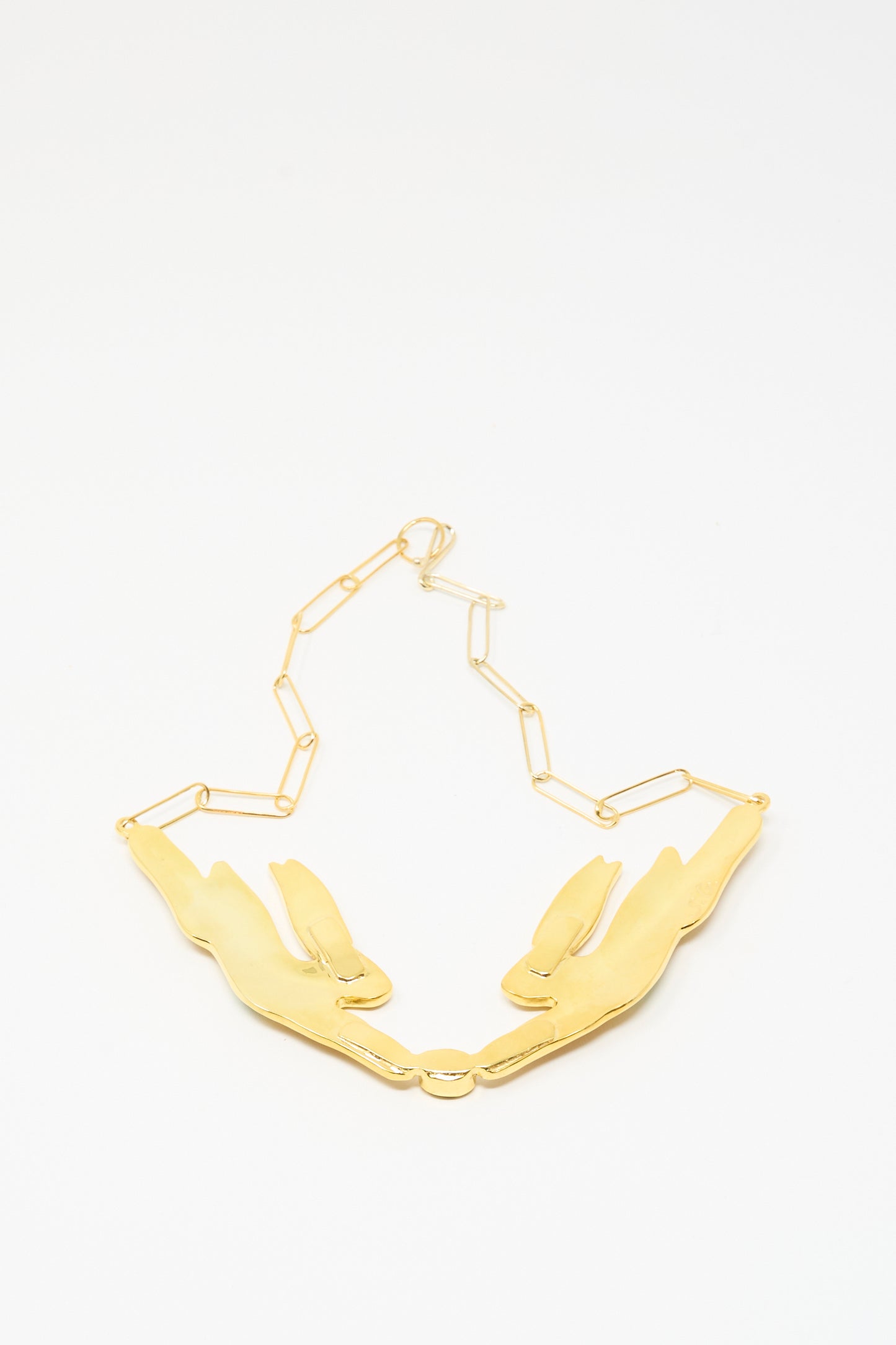 The Hare Necklace by Sofio Gongli features two 14K gold plated reclining rabbit pendants on a geometric chain, reminiscent of an enamel hare design, and is displayed on a white background.