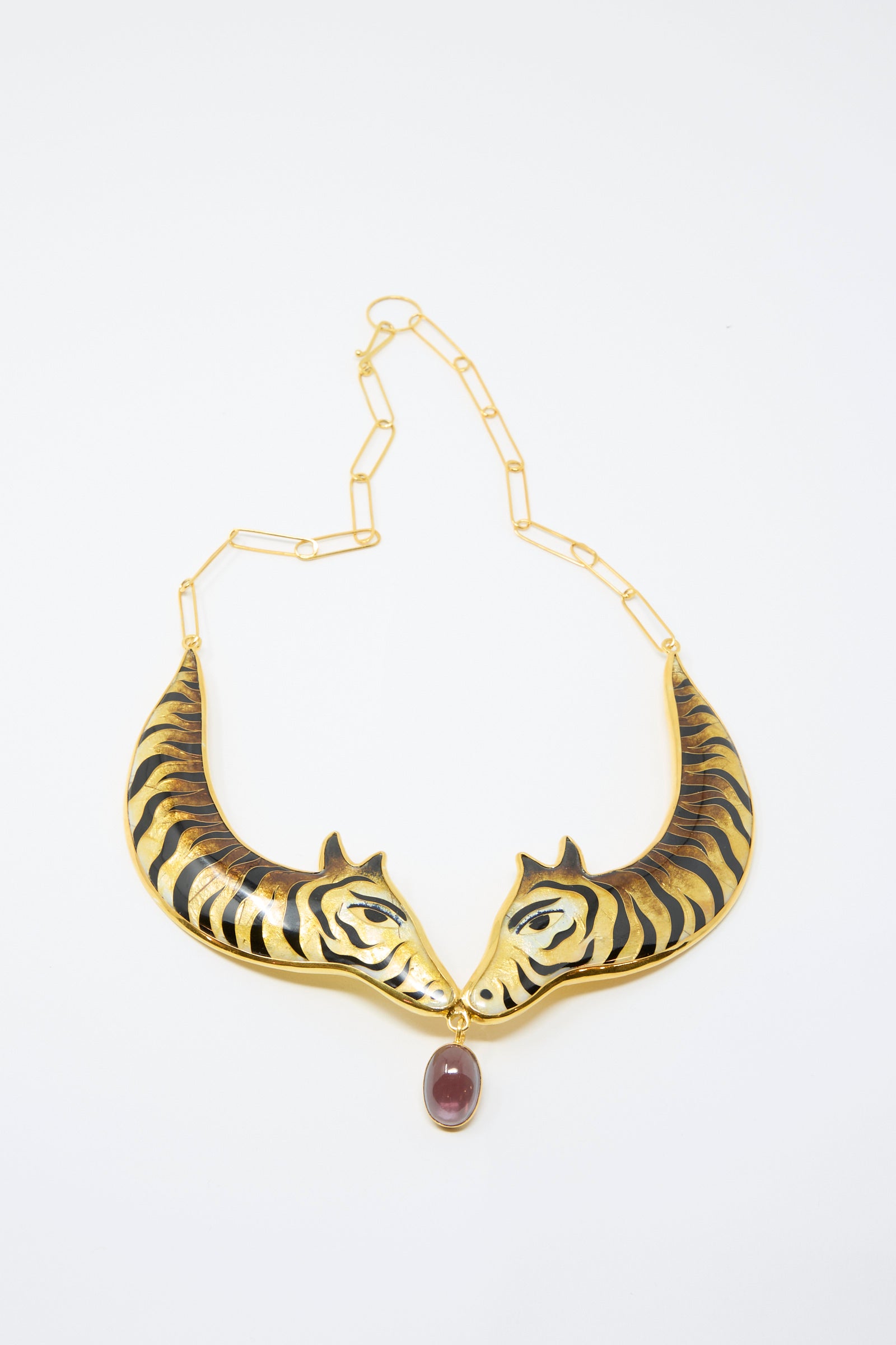 The Sofio Gongli Striped Animal Necklace features 14K gold-plated silver with tiger heads facing each other and a large purple corundum stone pendant.