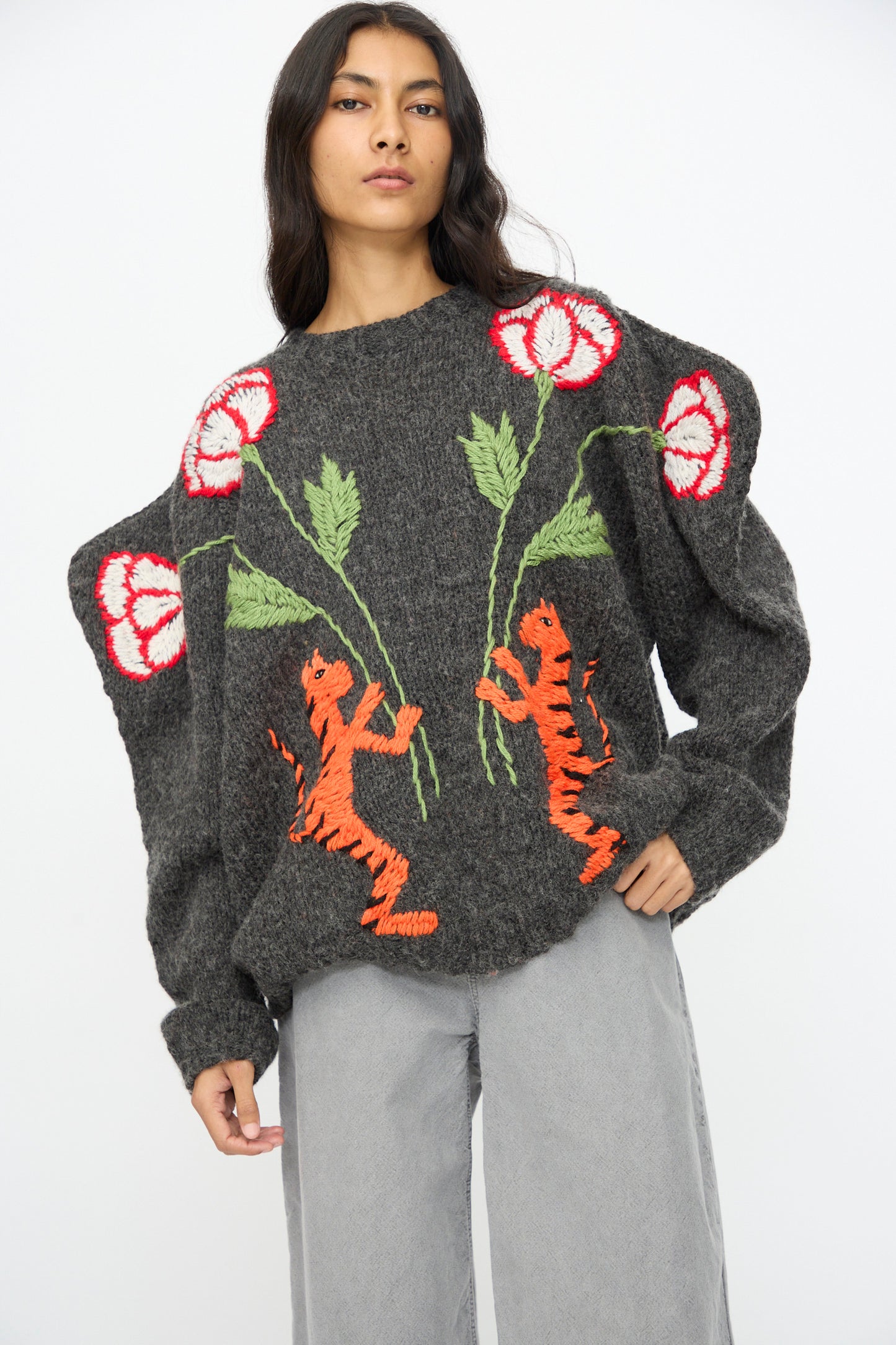 A woman models the Sofio Gongli Sweater in Charcoal with Tigers and Flowers—crafted from a mohair wool blend—paired with light grey wide-leg pants, set against a plain white background.
