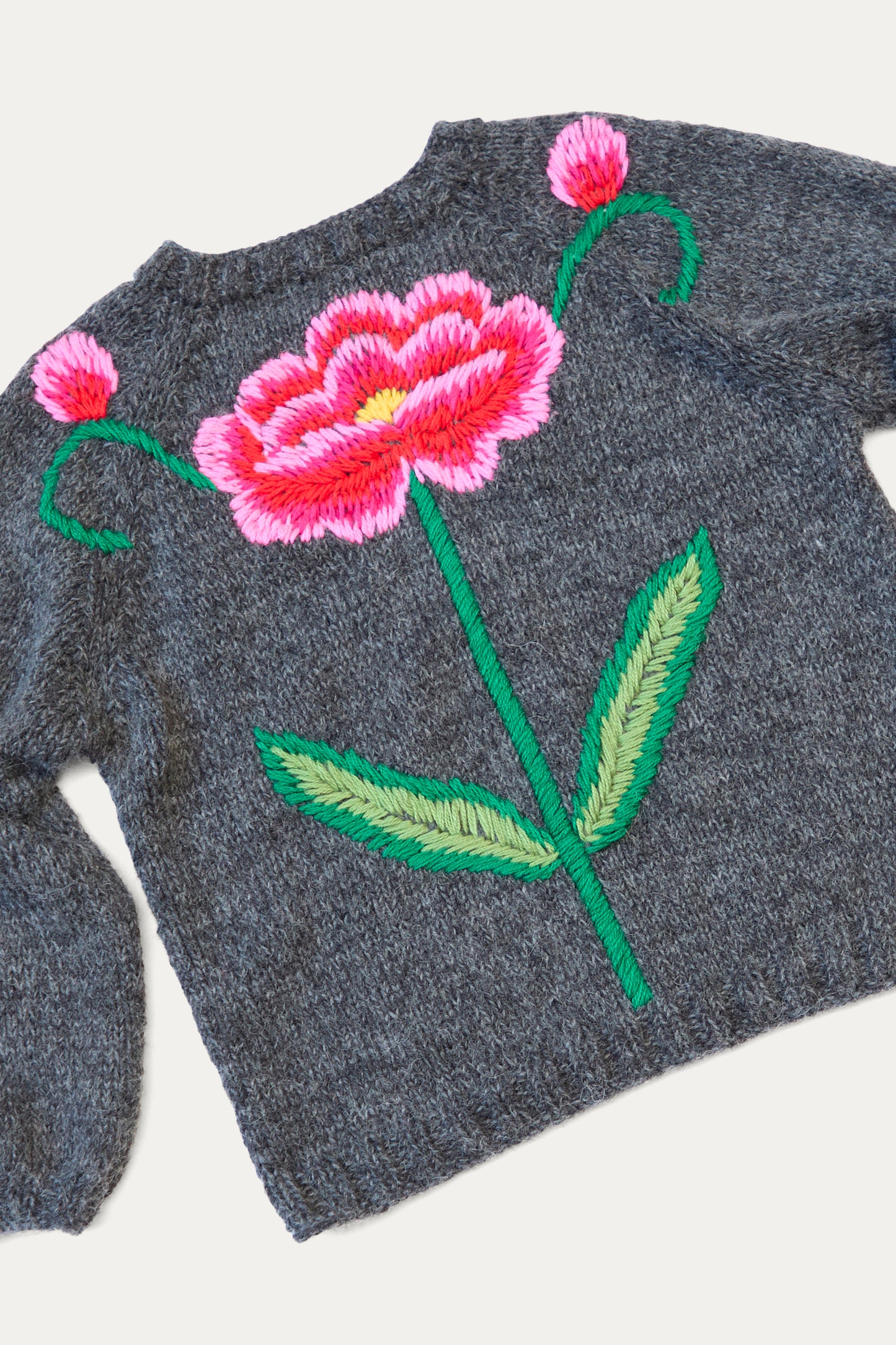 The Sofio Gongli sweater, made from a cozy mohair wool blend in charcoal, features an embroidered red and pink flower with vibrant green leaves and delicate pink buds on the back.