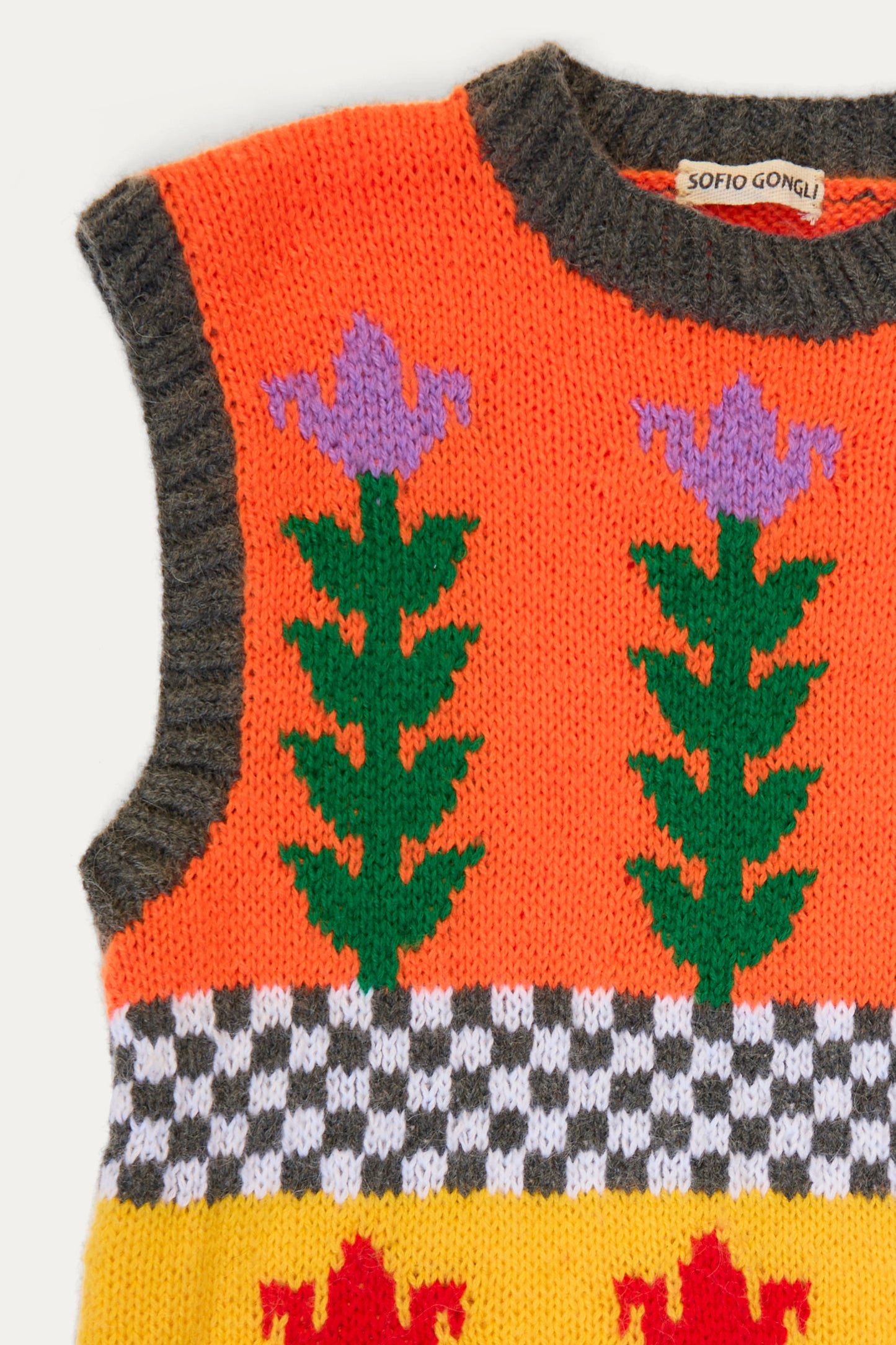 A close-up of a hand-knit sweater vest from Sofio Gongli with a flower checkered design in purple and green, featuring red motifs on a yellow backdrop. Made from a mohair wool blend, it includes unique black-and-white stripes. 