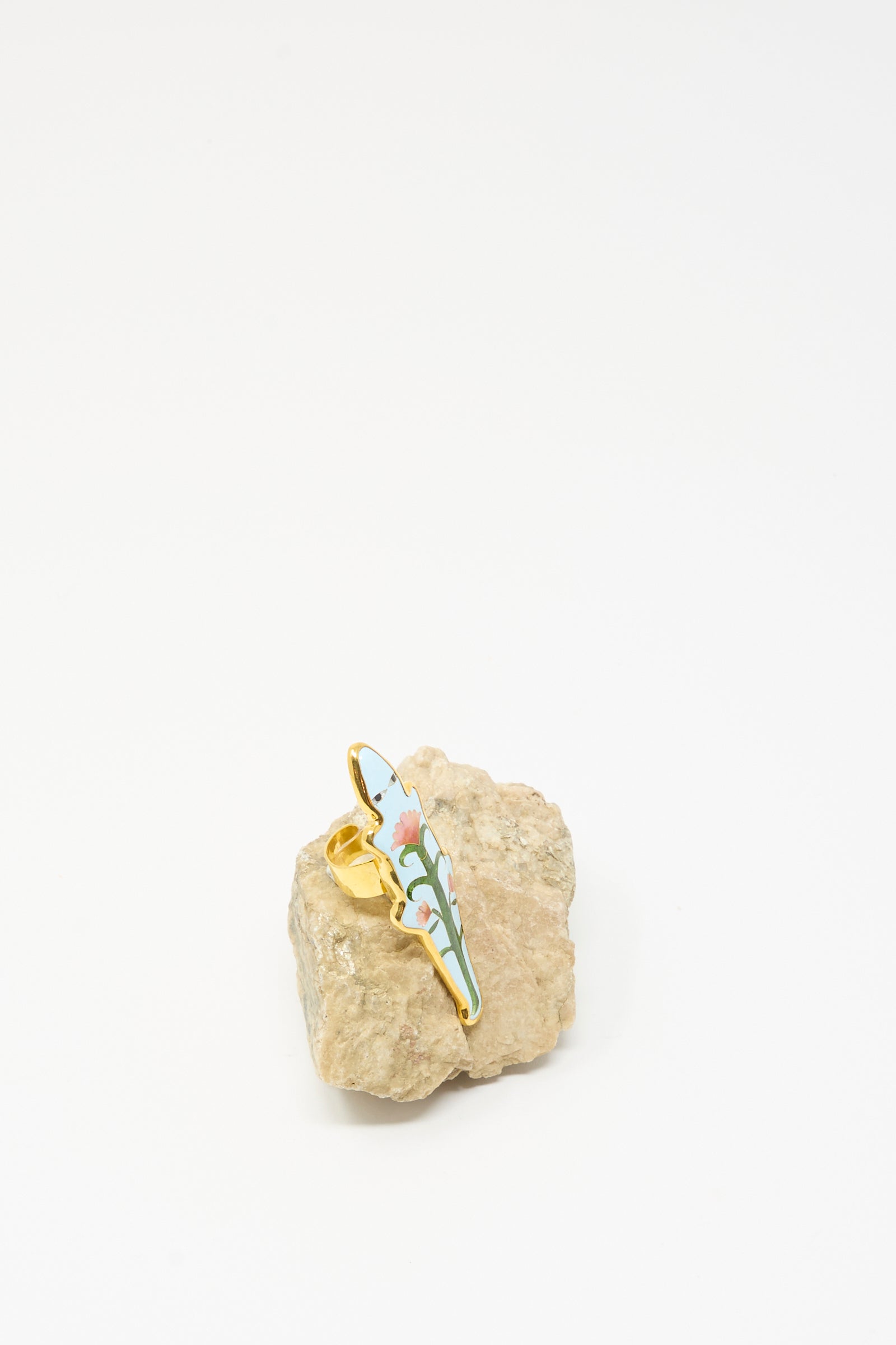 The Sofio Gongli Alligator Ring in Blue stands upright on a rough, light-colored stone against a plain white background.