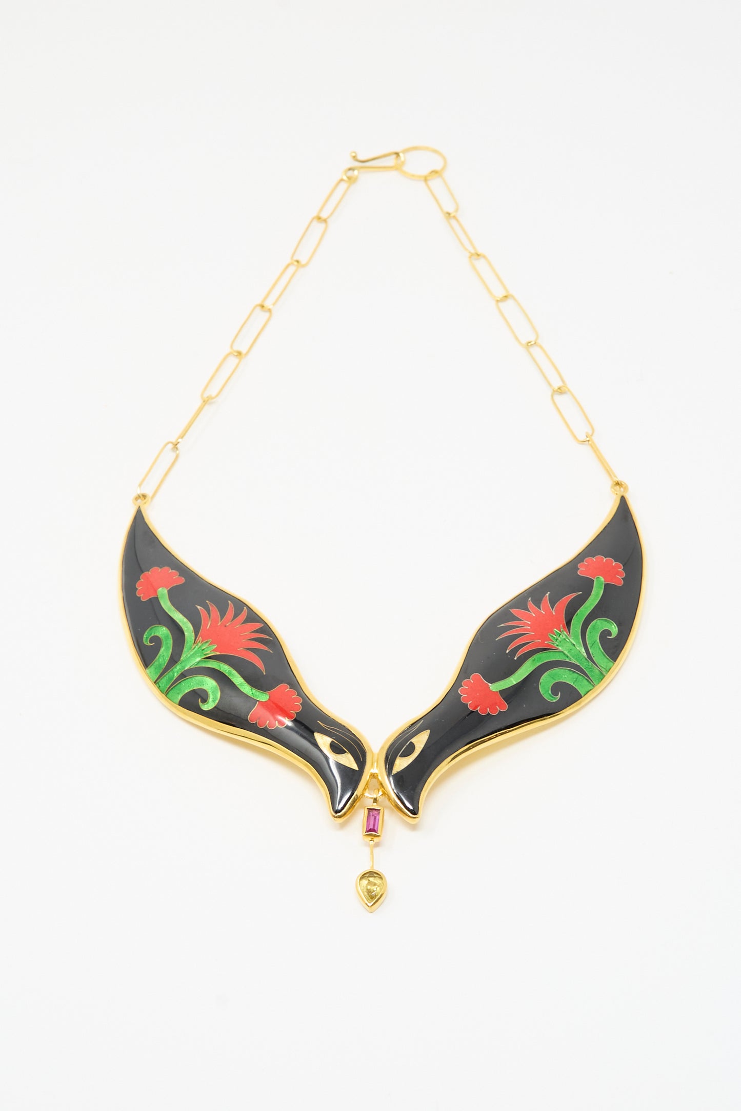 The Sofio Gongli Bird Necklace in Black and Red Flower features a gold chain with two black enamel bird pendants, red and green floral accents, centered by a pink gem and gold heart charm.