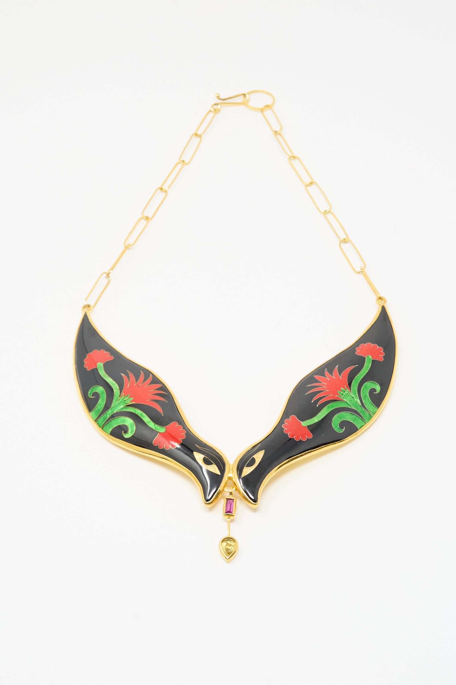 The Sofio Gongli Bird Necklace in Black and Red Flower features a gold chain with two black enamel bird pendants, red and green floral accents, centered by a pink gem and gold heart charm.