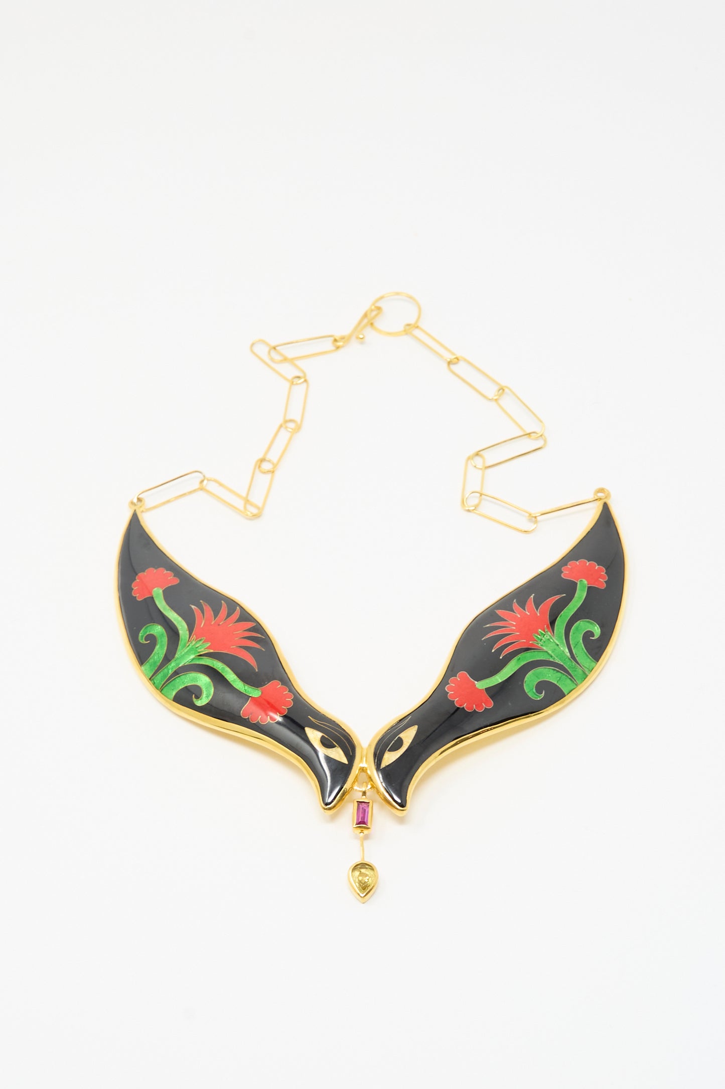 The Sofio Gongli Bird Necklace in Black and Red Flower features two black, wing-shaped pendants with red and green floral designs, joined by a small gold and red centerpiece on a gold chain.