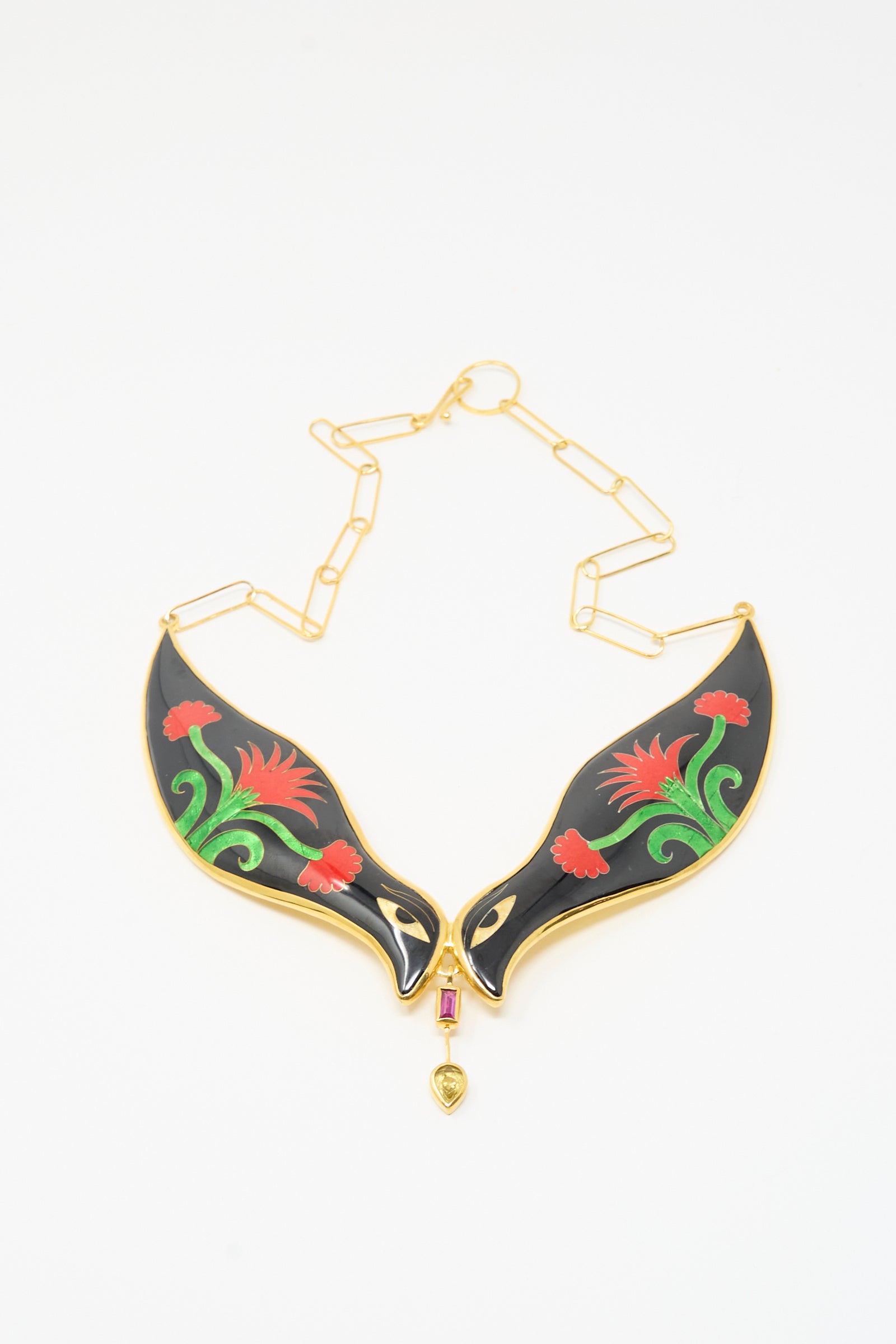 The Sofio Gongli Bird Necklace in Black and Red Flower features two black, wing-shaped pendants with red and green floral designs, joined by a small gold and red centerpiece on a gold chain.