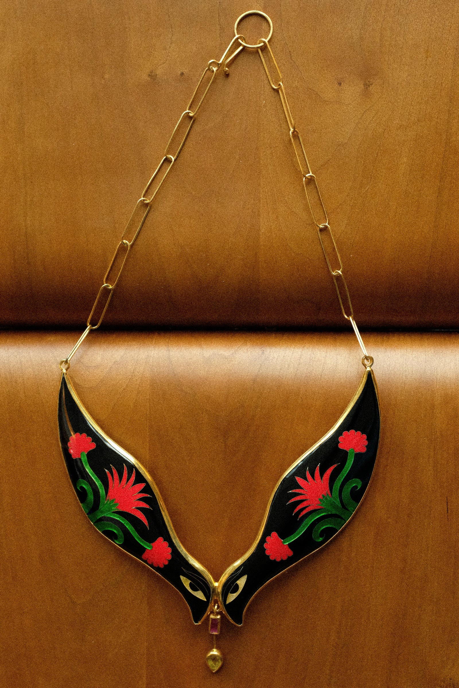 Sofio Gongli's Bird Necklace on a wooden stool.