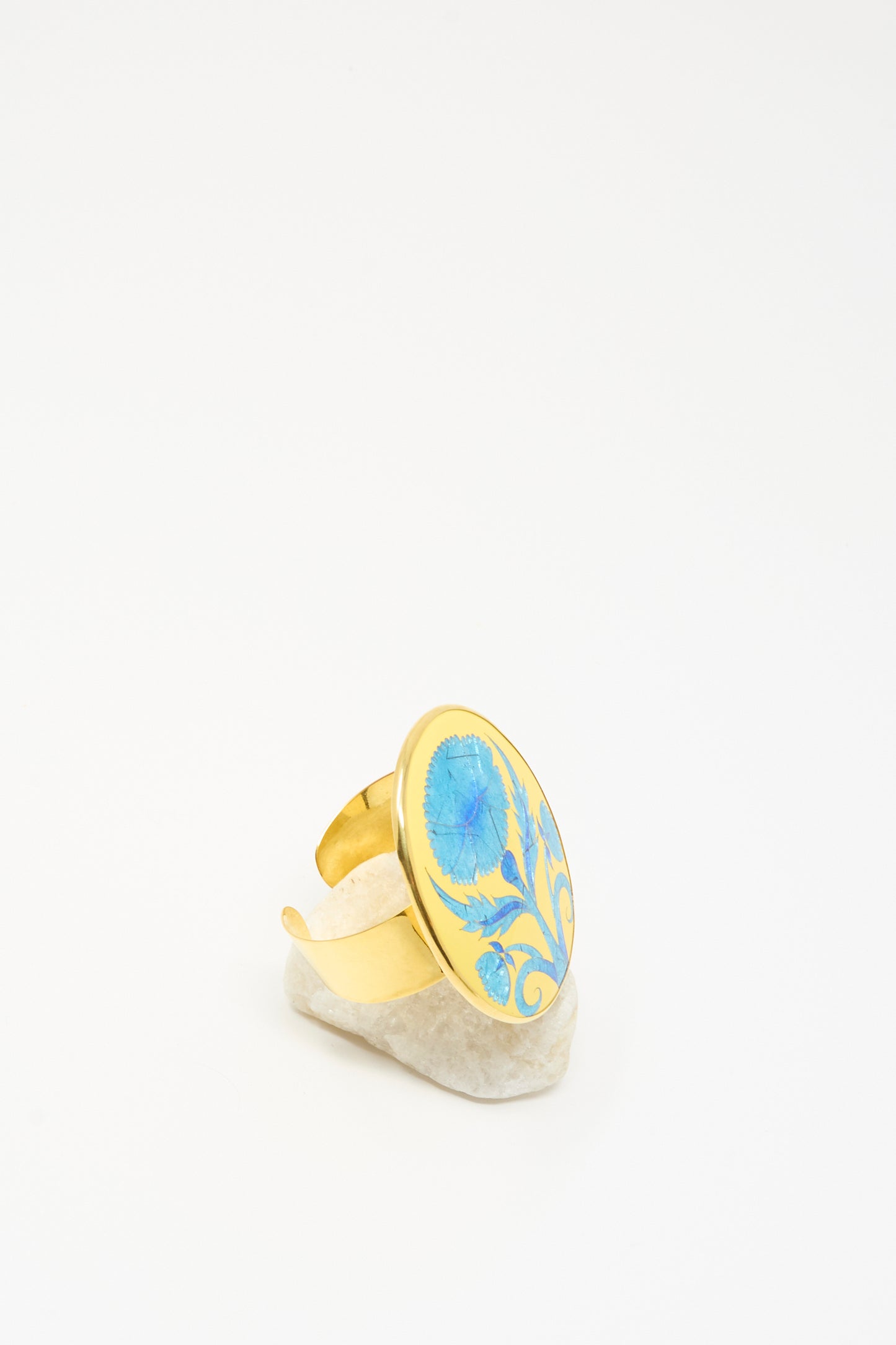 Sofio Gongli's Flower Bracelet in Blue features an elegant floral pattern, showcased upright on a white stone with a minimalist background.