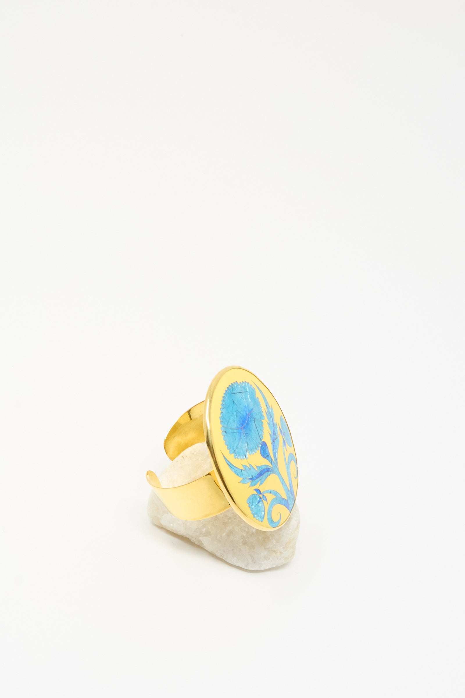 Sofio Gongli's Flower Bracelet in Blue features an elegant floral pattern, showcased upright on a white stone with a minimalist background.