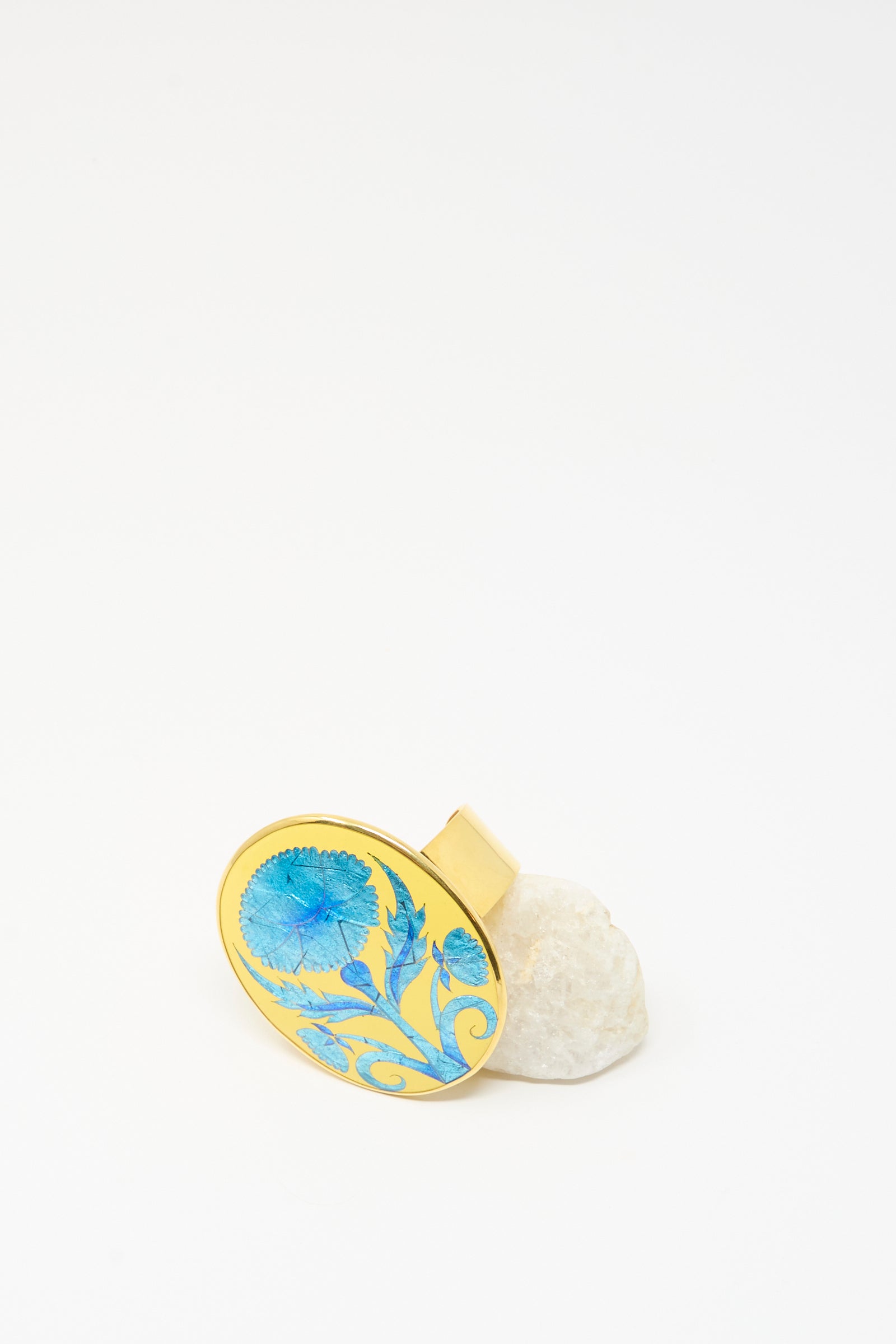 The Sofio Gongli Flower Bracelet in Blue is inspired by Byzantine cloisonné art, featuring a blue floral design, and is displayed upright on a white stone with a clean white background.