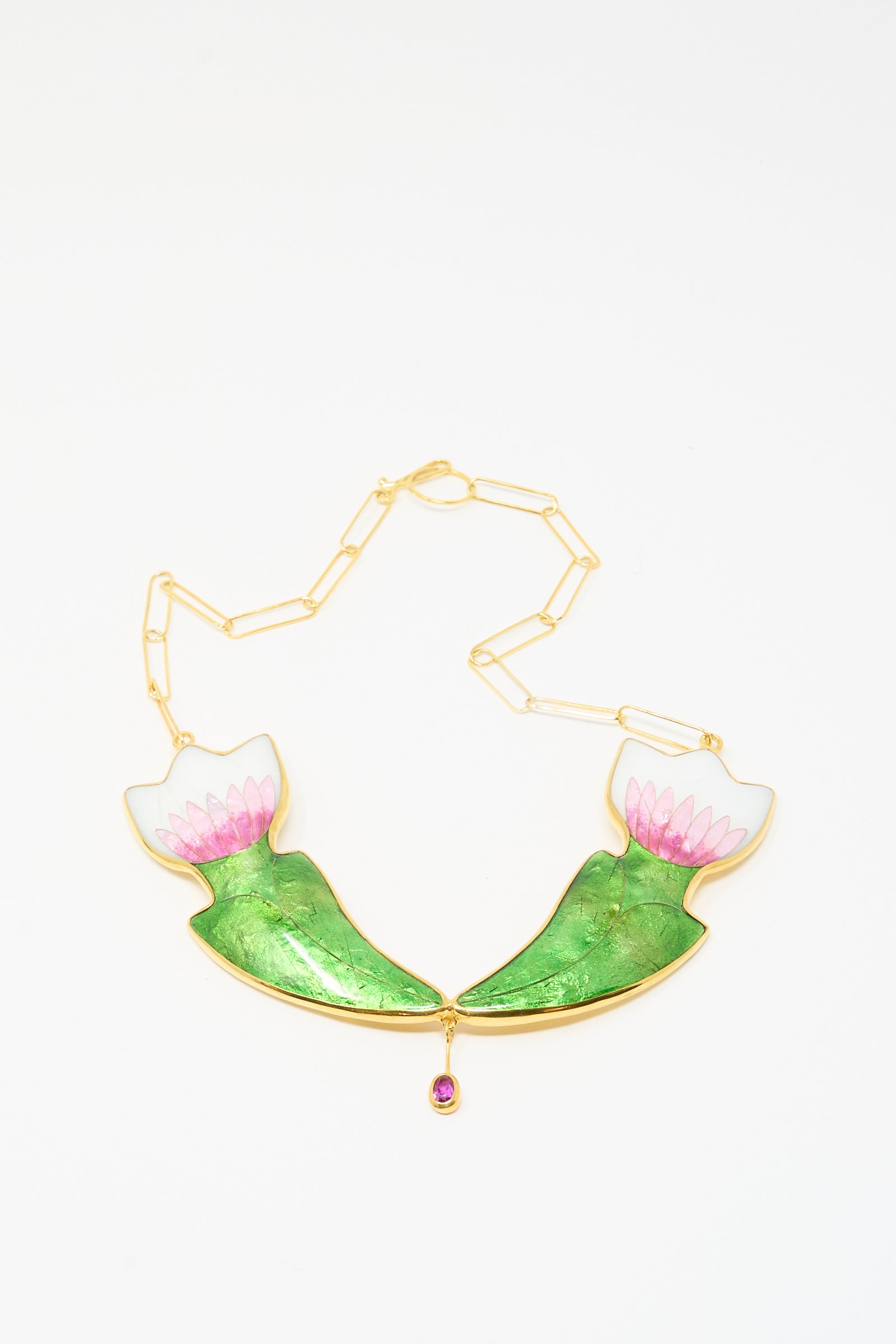 The Sofio Gongli Flower Necklace features two green and pink enamel lotus motifs with a pink gemstone drop pendant. This piece is 14k gold plated and shown against a white background.