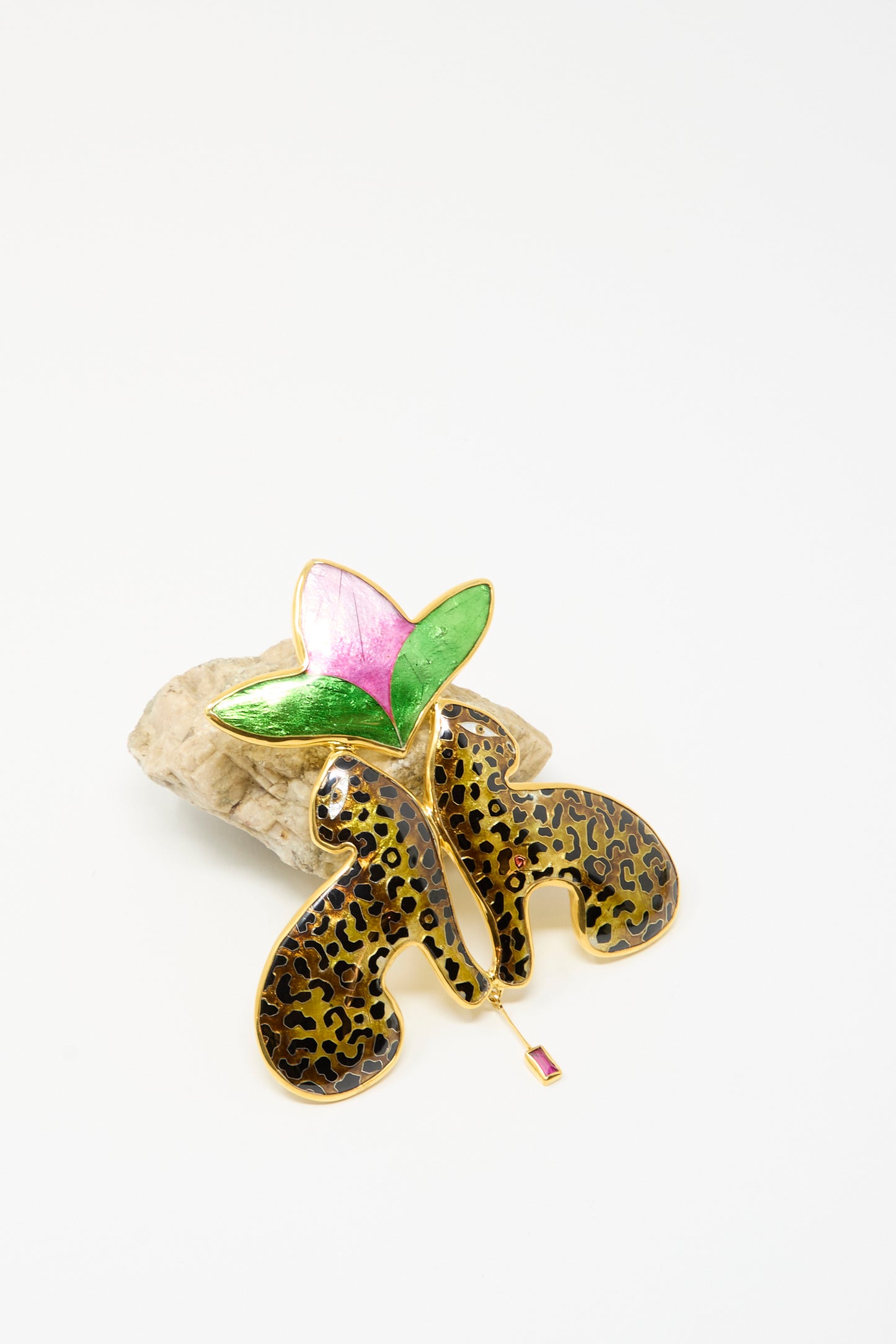 The Sofio Gongli Leopard and Flower Pendant features two 14K gold plated black leopards sitting back to back beneath a large pink and green flower, displayed on a neutral stone background.