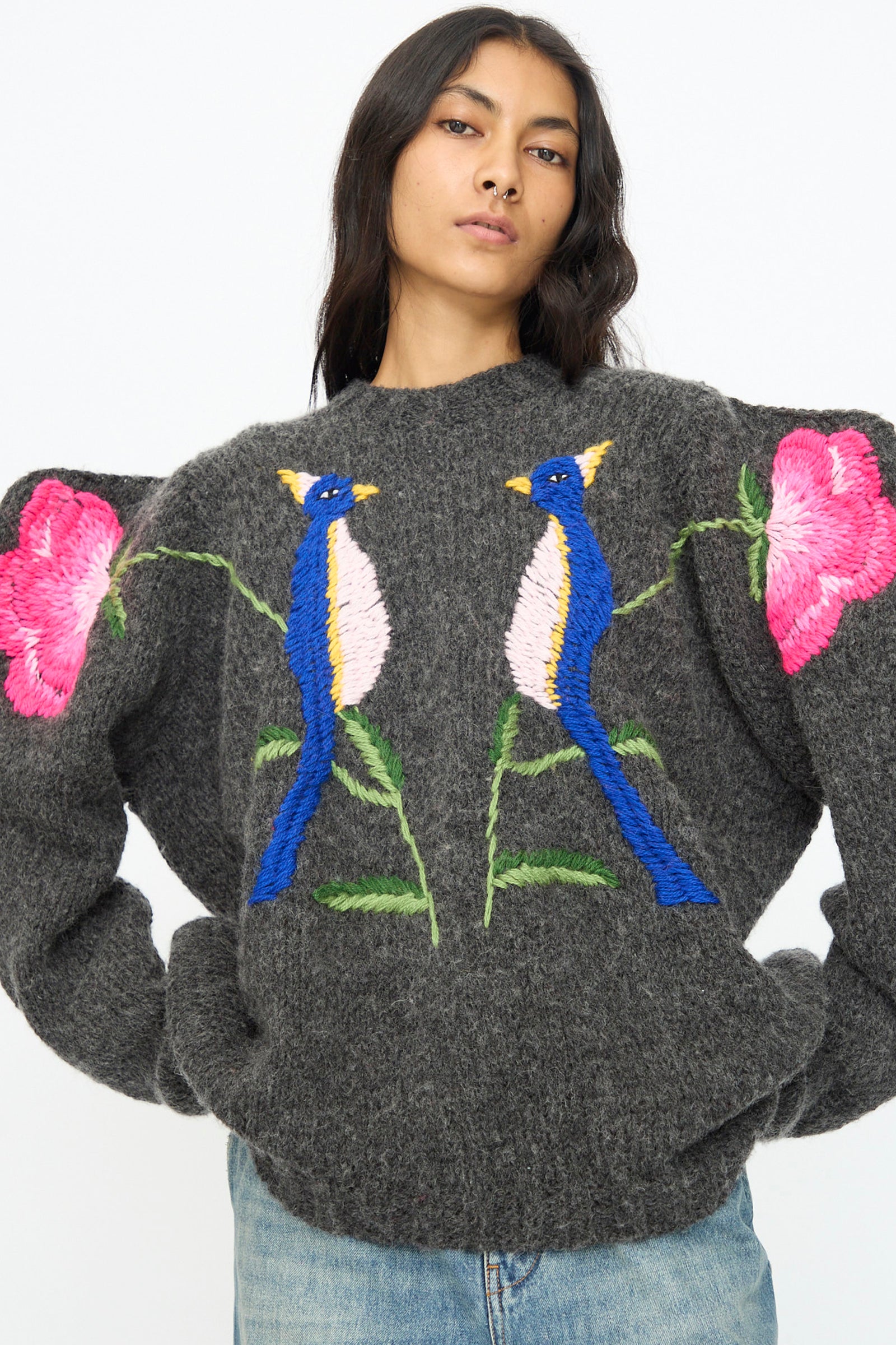 A woman wearing the Sofio Gongli Sweater in Charcoal with Birds and Flowers against a white background.