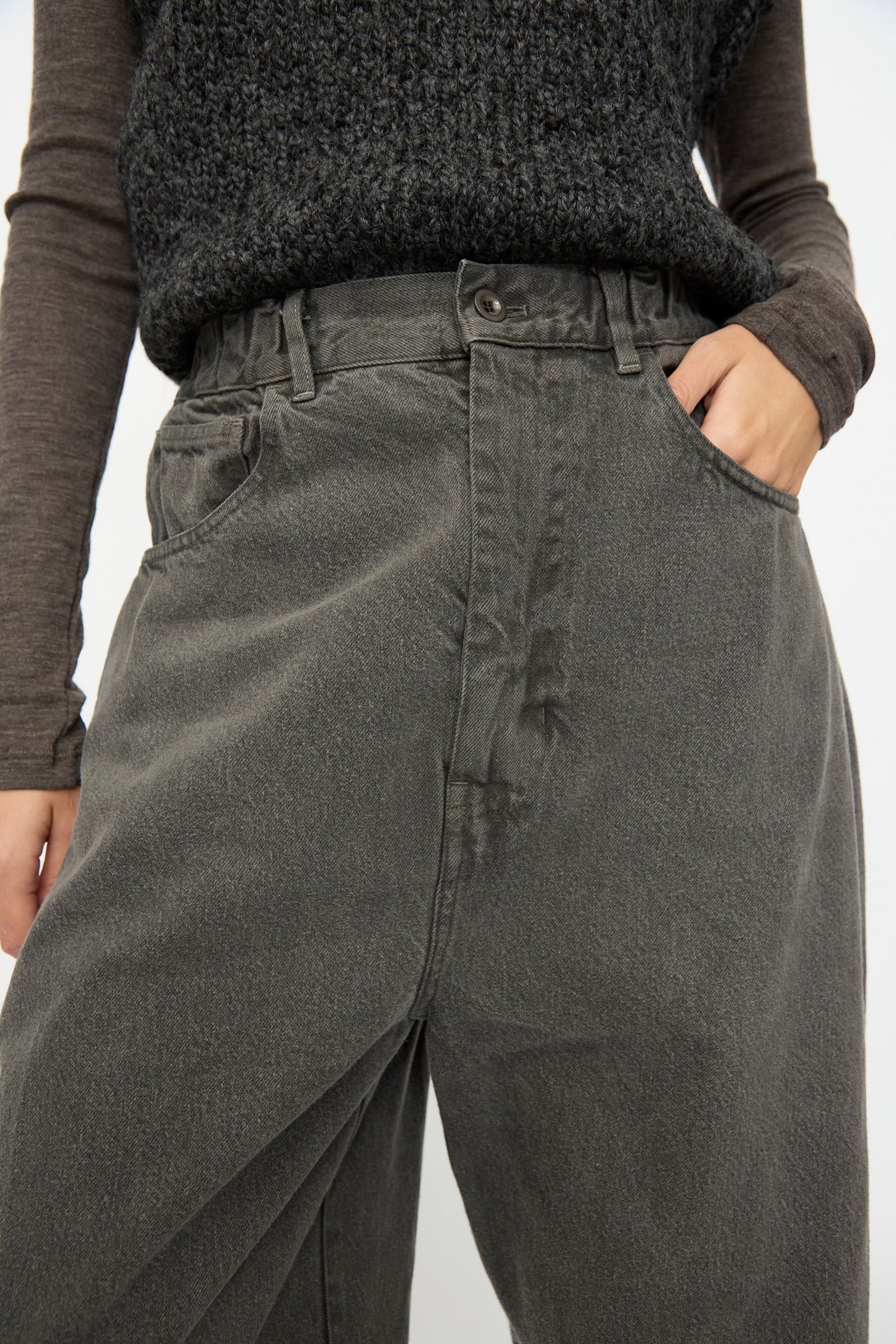 A person wearing SONO’s Cotton Jah Jeans in Off Black—high-waisted, loose-fit organic cotton denim—paired with a textured dark sweater and one hand in the pocket.