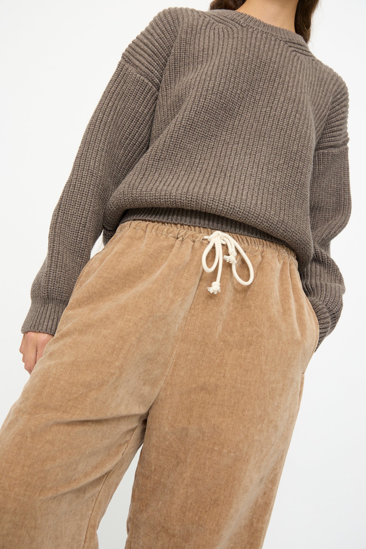 A person wears the SONO Johnny Jogger in Desert Rose, featuring a relaxed fit and drawstring waist, crafted from a cotton linen blend, standing against a plain light background.