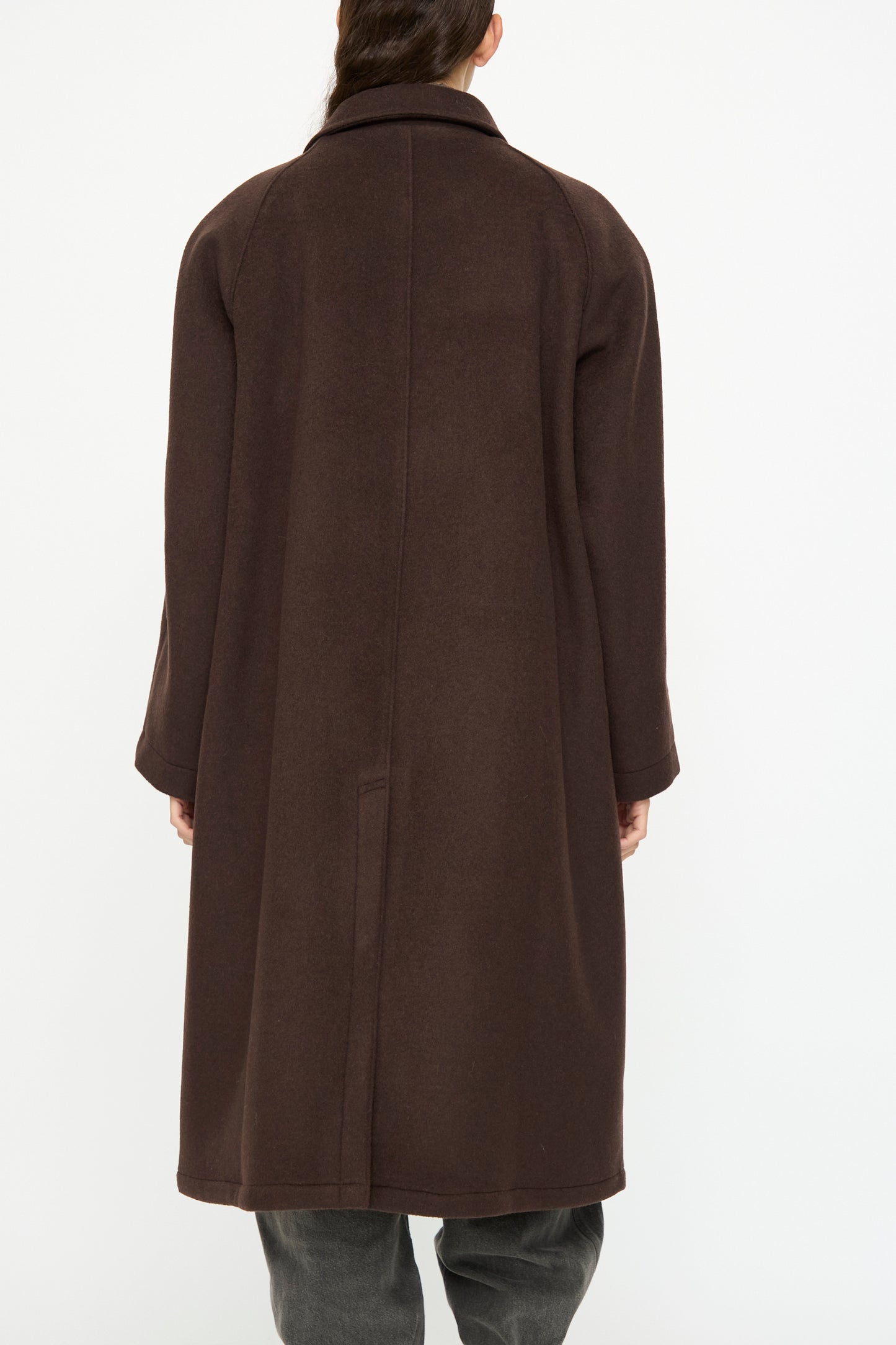 A person wearing the SONO Recycled Wool Carl Coat in Earth stands facing away from the camera against a plain white background.