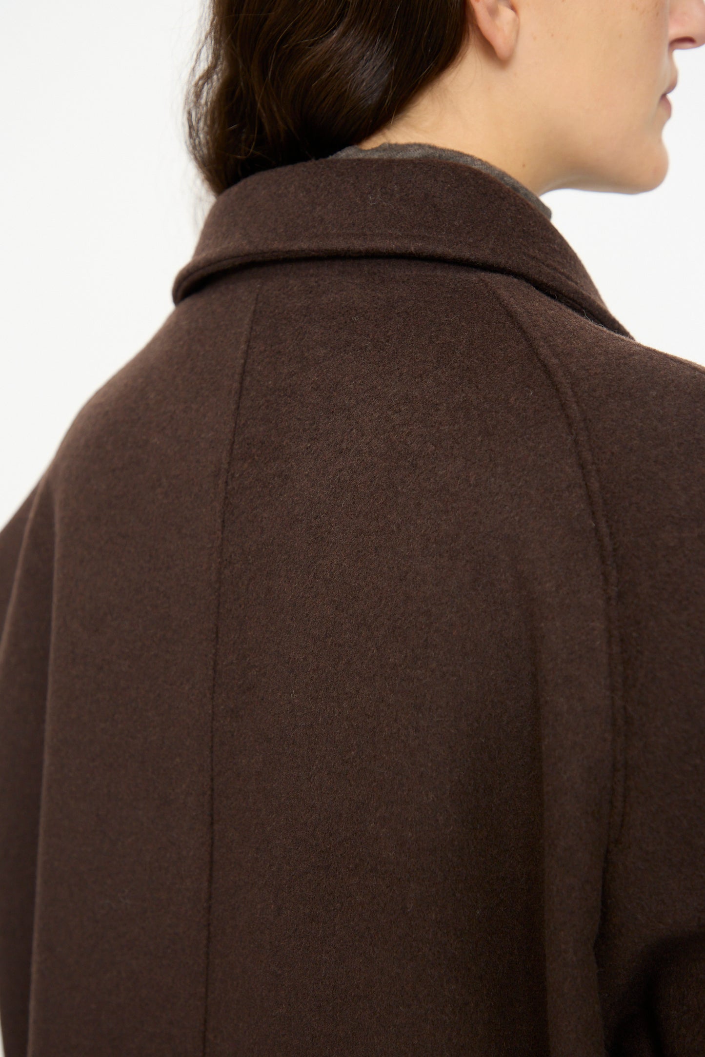 Close-up of a person wearing the SONO Recycled Wool Carl Coat in Earth, shown from the back and side, highlighting the collar and shoulder details.