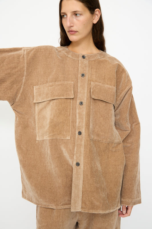 A person wears the SONO Sid Shirt in Desert Rose, a relaxed fit, oversized light brown corduroy button-down with large front pockets and dark buttons, standing against a plain white background.