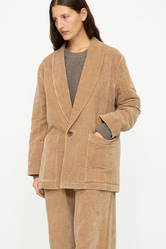 A person wears the SONO Yoyogi Jacket in Desert Rose, styled with matching pants and a gray knit sweater, posed against a plain white background.